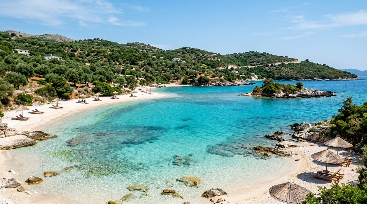 Bucht der albanischen Riviera bei Ksamil, kristallklares türkisfarbenes Wasser, weißer Sand und Olivenhügel