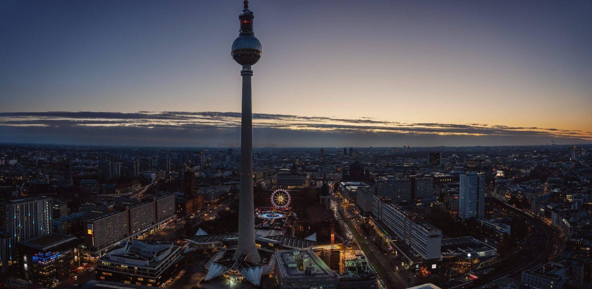 Vue panoramique au crépuscule d’une grande tour de télévision dominant une métropole allemande avec grande roue illuminée