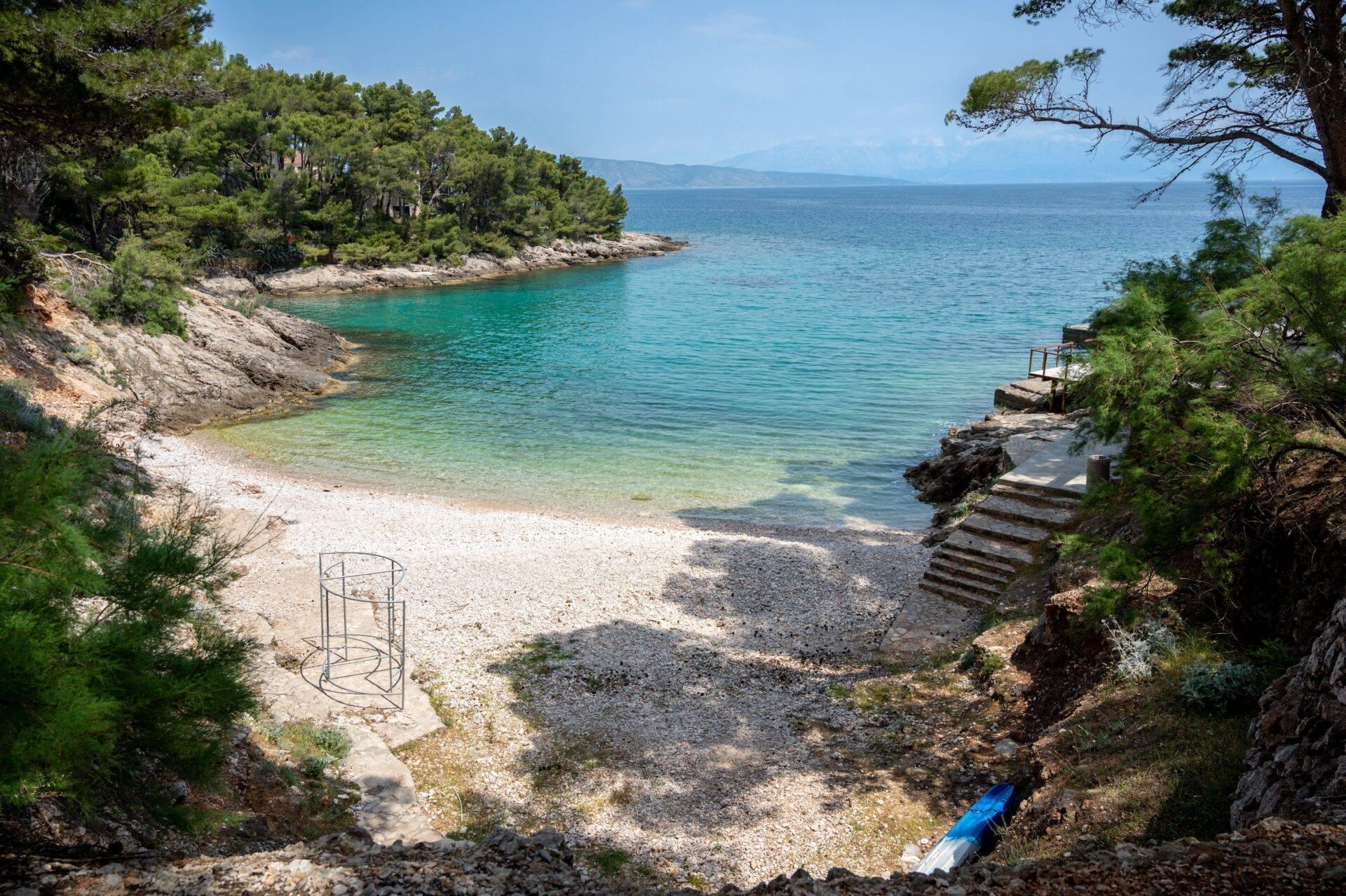 Petite crique méditerranéenne avec plage de galets, eaux turquoise et falaises boisées en Croatie