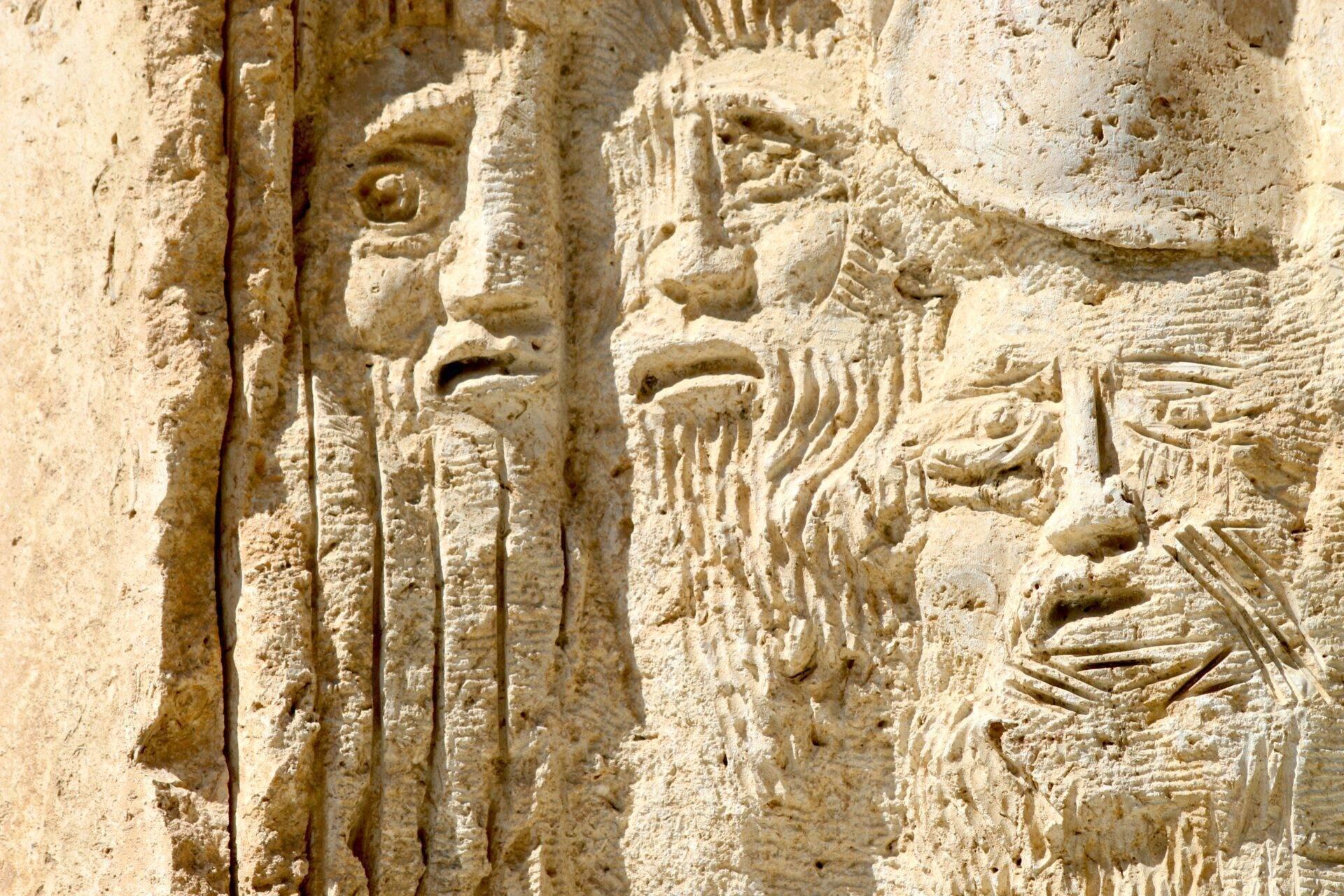 Bas-relief en pierre calcaire représentant des figures humaines et des inscriptions anciennes gravées sur une façade de temple historique