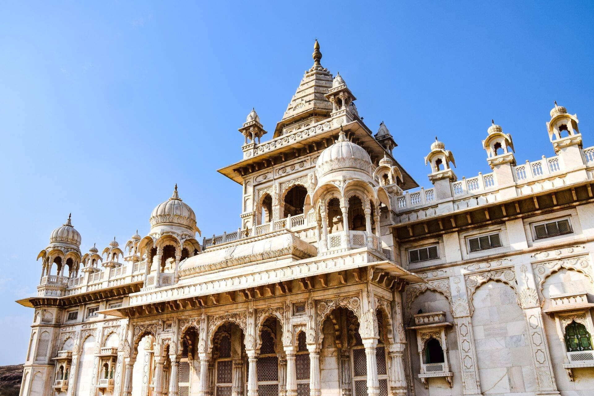 Un temple hindou blanc et or avec dômes et tourelles ornementales sous un ciel bleu dégagé
