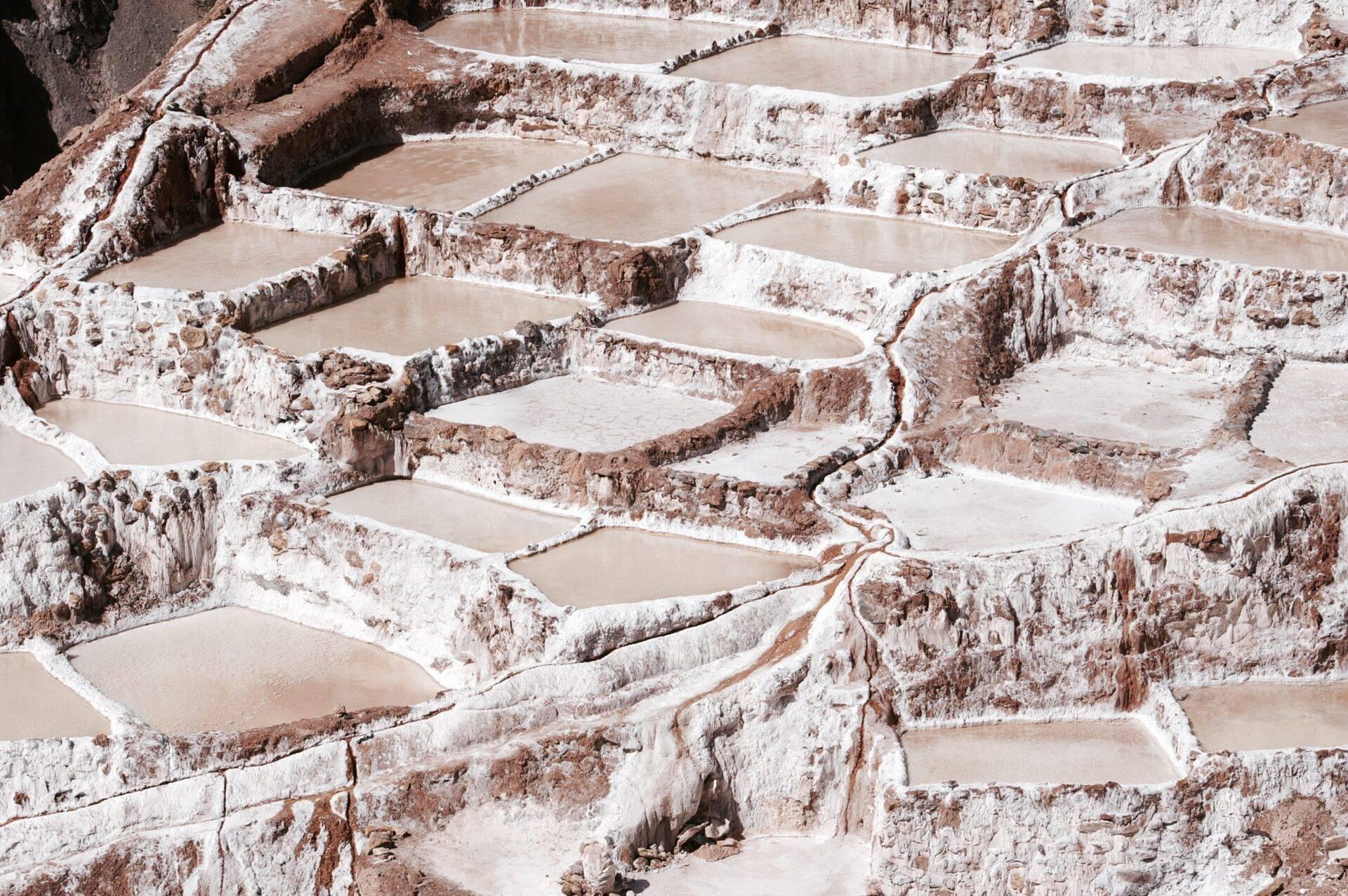 Terrasses de bassins minéraux blanc et roux en cascade dans les Andes péruviennes, formant un paysage géothermique spectaculaire
