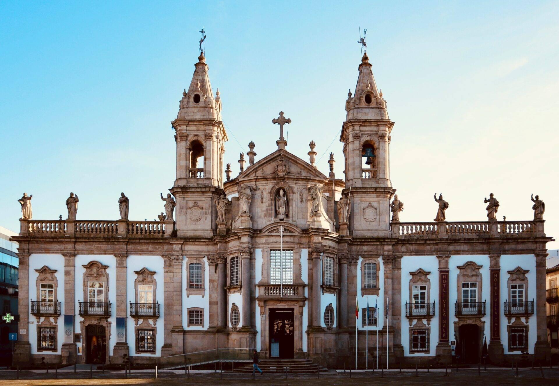 Façade blanche et dorée d’une église coloniale baroque avec deux clochers jumelés et statues religieuses
