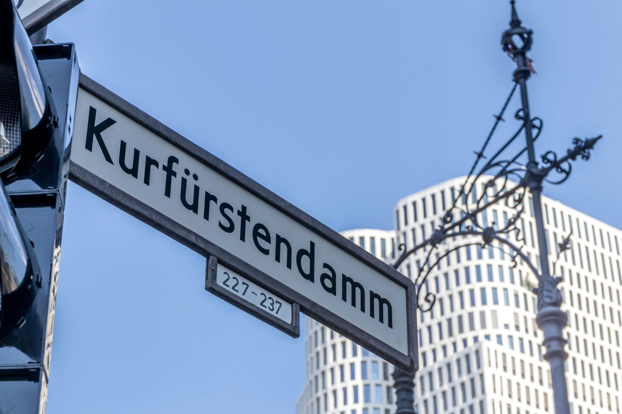 Plaque de rue Kurfürstendamm avec numéros 227-237 et bâtiments modernes berlinois en arrière-plan sous ciel bleu