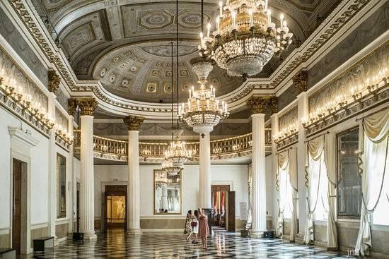 Grand salle de palais avec colonnes blanches, lustres en cristal et plafond ornementé à décoration dorée