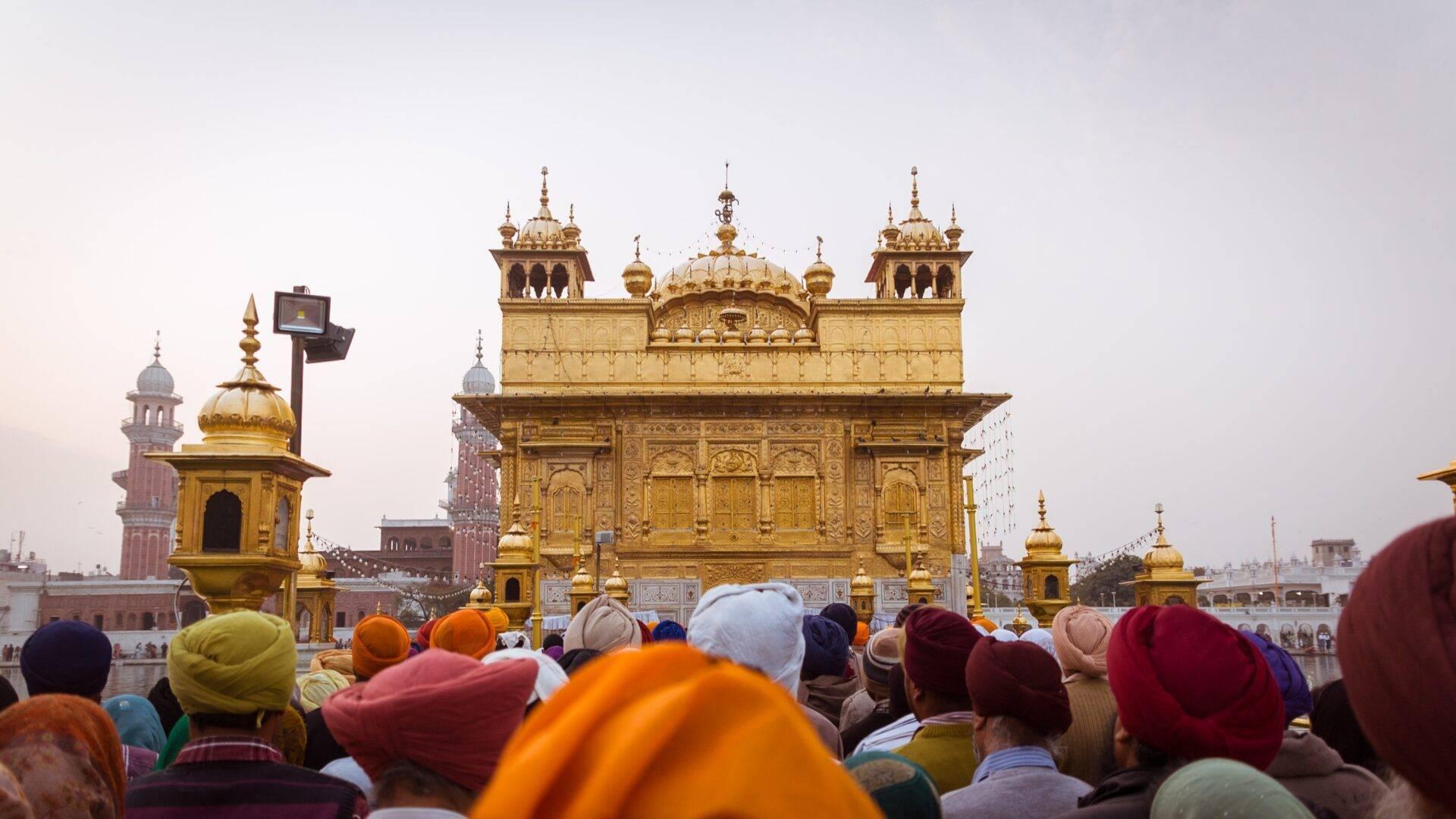 Une foule de pèlerins en turbans colorés face à un temple doré aux architectures élaborées et dômes dorés