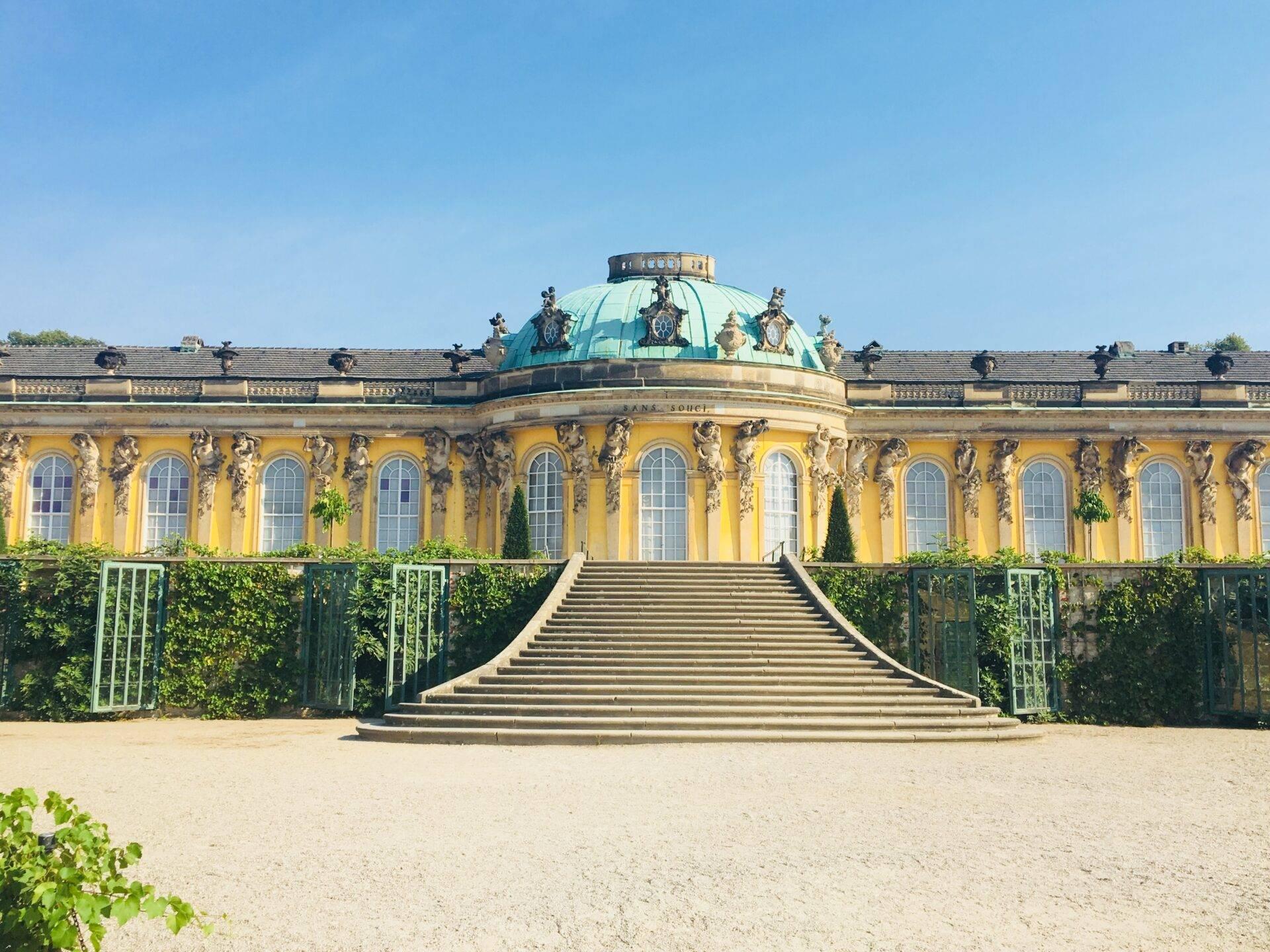 Un palais baroque jaune orné d’une coupole verte turquoise avec escalier monumental en pierre