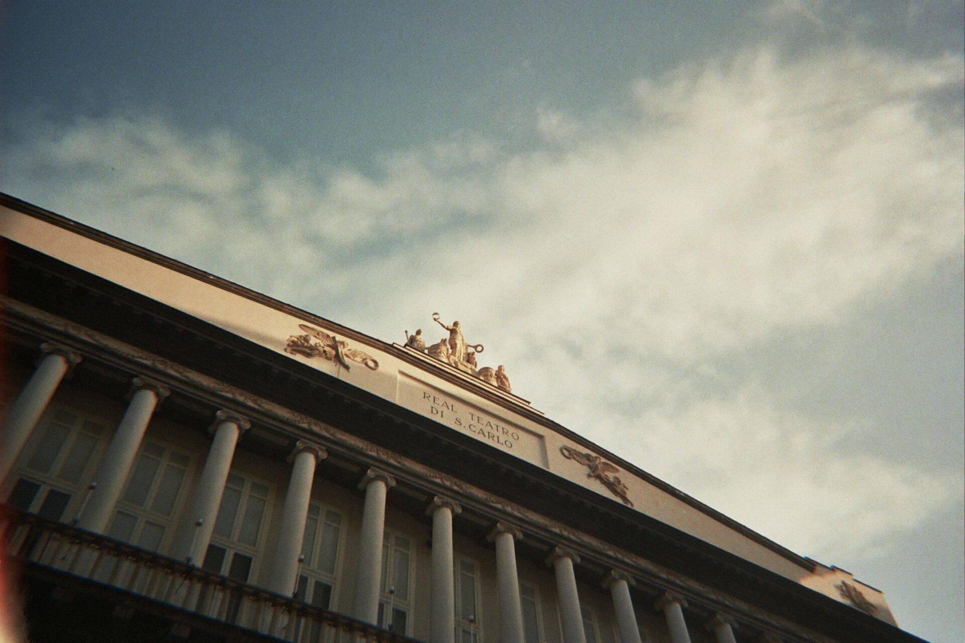 Façade d’un théâtre italien historique avec colonnes classiques et statues dorées sur le toit