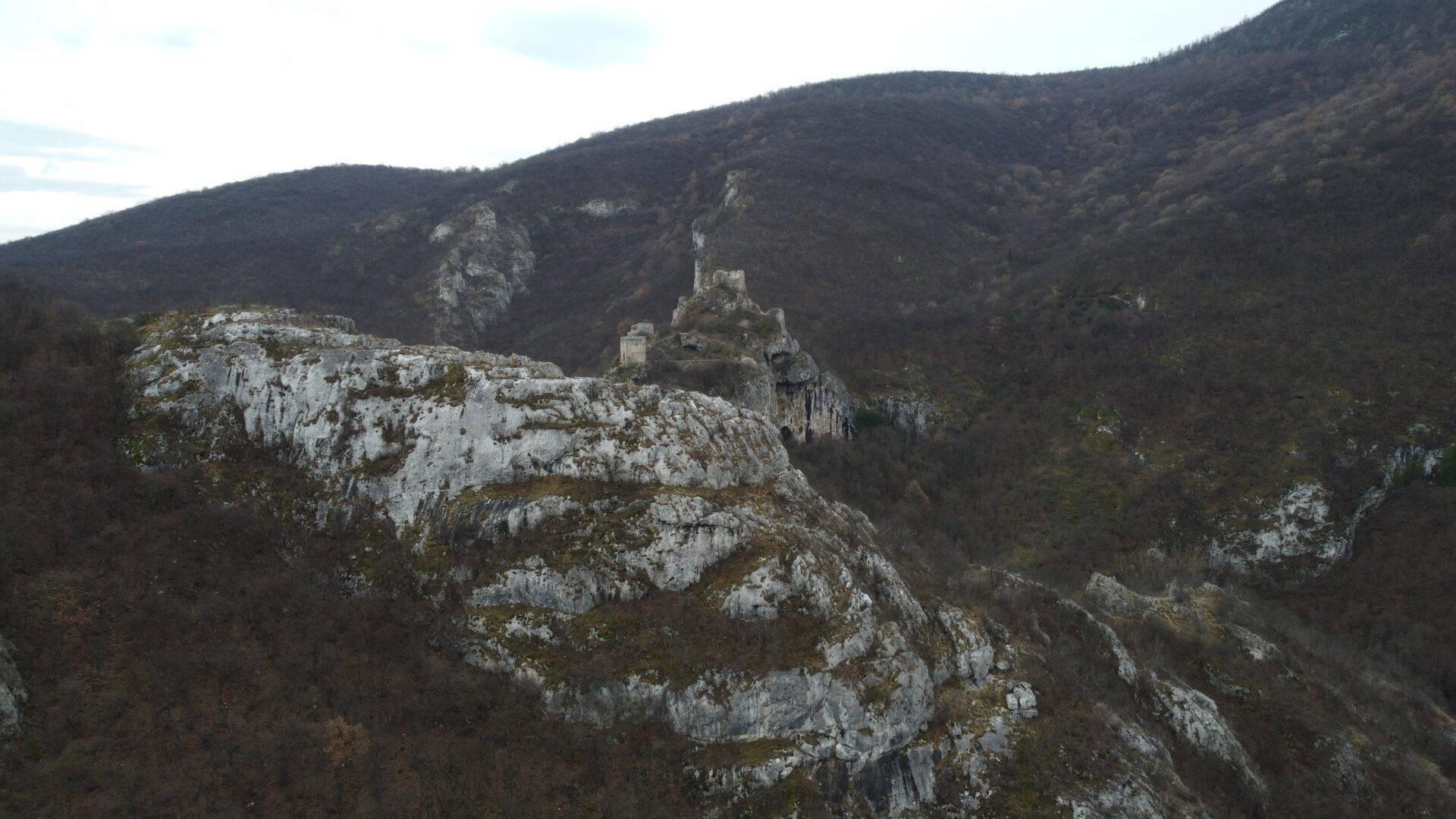 Ruines d’un château médiéval perché sur un rocher calcaire dominant une vallée boisée et montagneuse