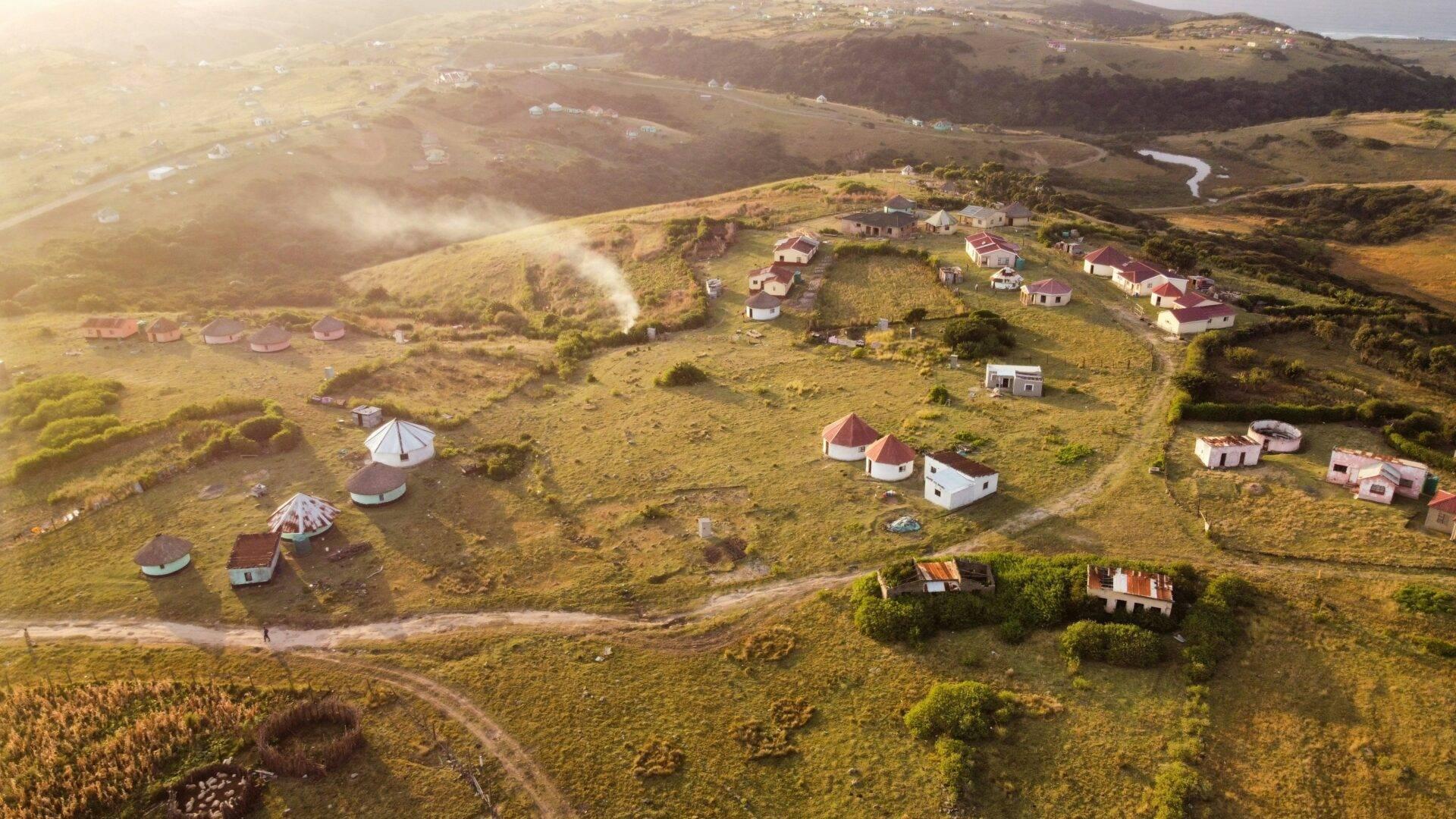 Vue aérienne d’un village géothermique avec des maisons aux toits rouges dispersées dans des terres verdoyantes et vallonnées