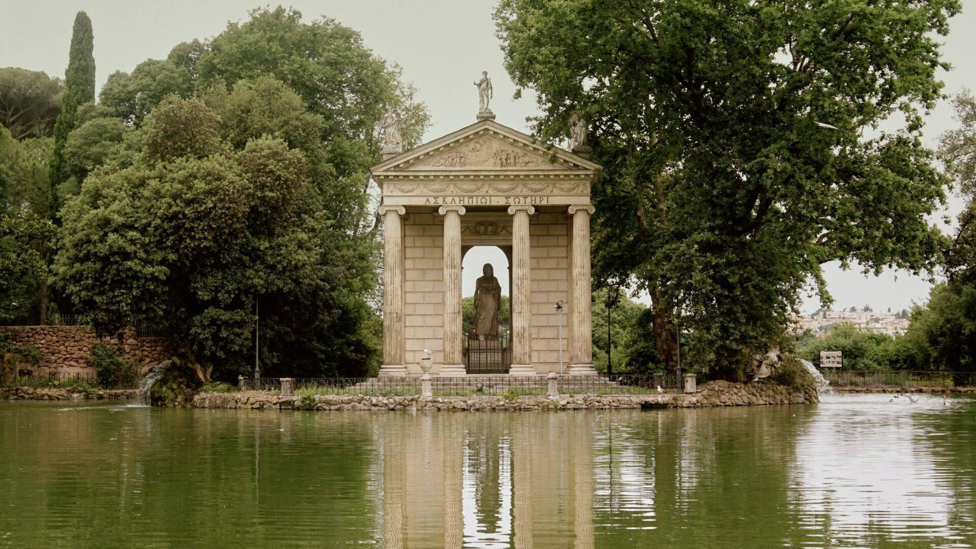 Un temple néoclassique aux colonnes blanches se dresse au bord d’une rivière, entouré de végétation luxuriante