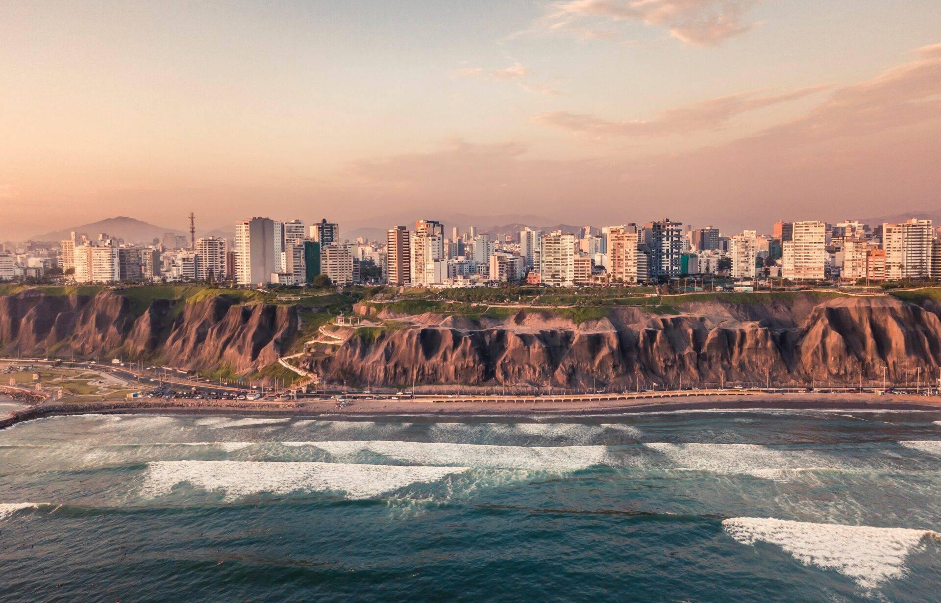 Vue côtière d’une ville moderne avec falaises ocre dominant une plage de sable et l’océan Pacifique