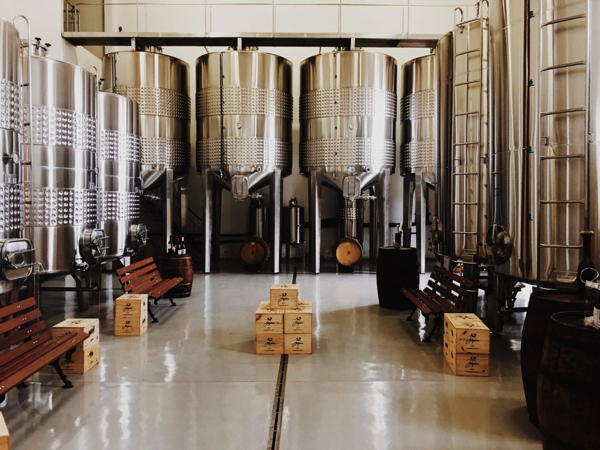Intérieur moderne d’une cave viticole avec cuves de fermentation en acier inoxydable et mobilier en bois
