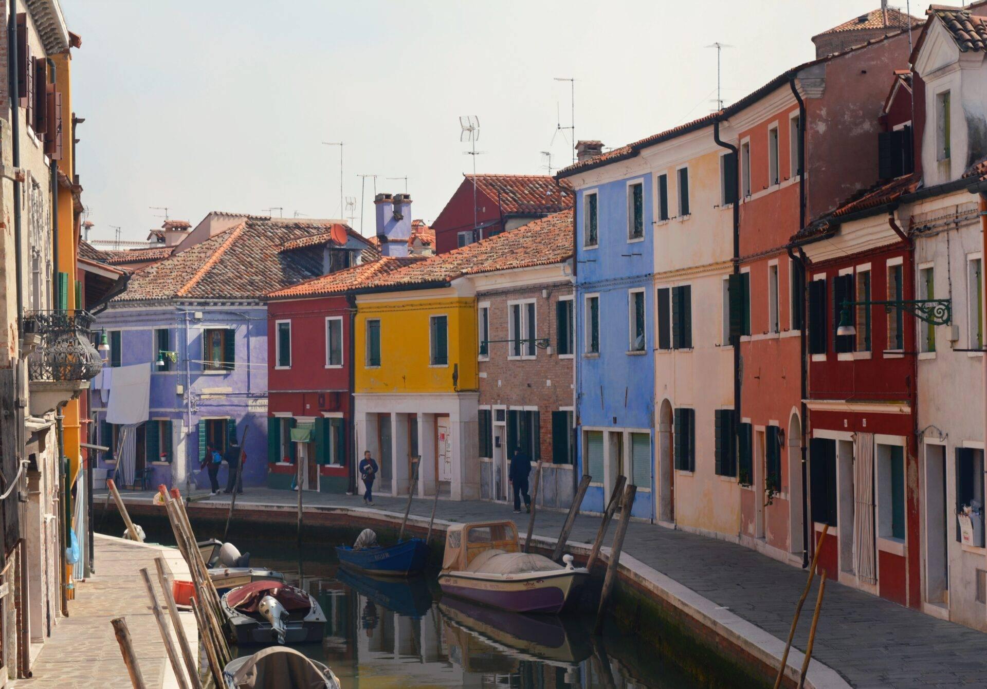 Des maisons colorées aux façades vibrantes bordent un canal avec des barques de pêche amarrées