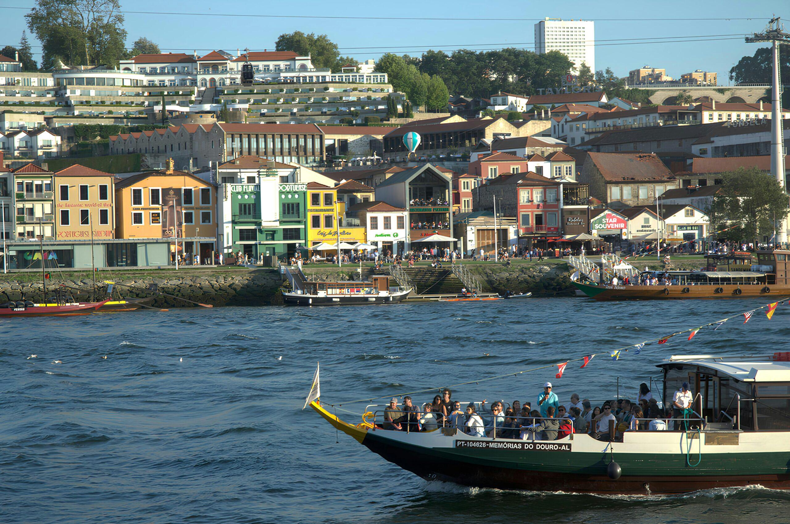 Un bateau de tourisme coloré navigue sur un fleuve face à des façades pittoresques en bord de quai animé