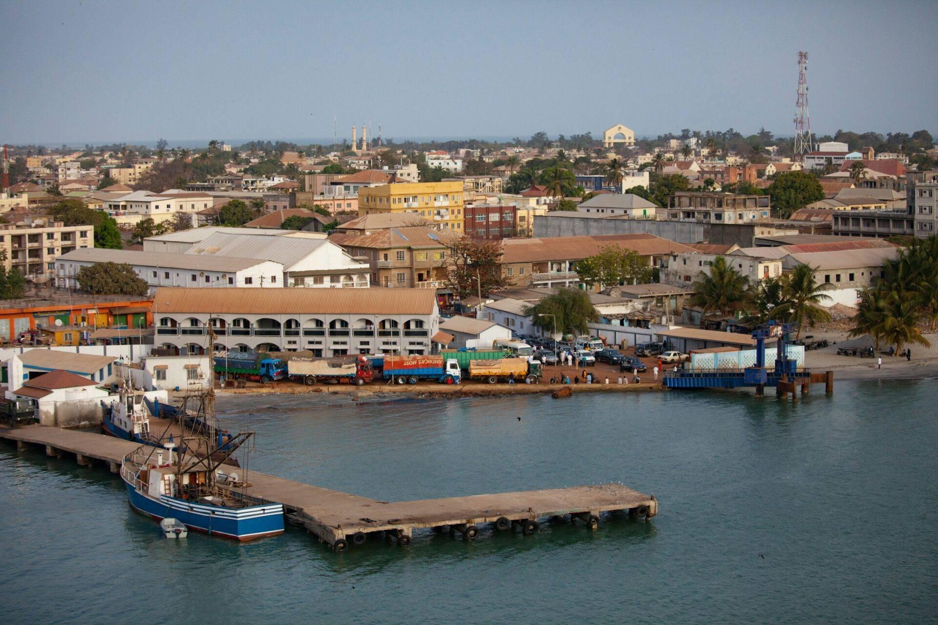 Vue panoramique d’un port fluvial africain avec bateaux, entrepôts colorés et ville étendue en arrière-plan