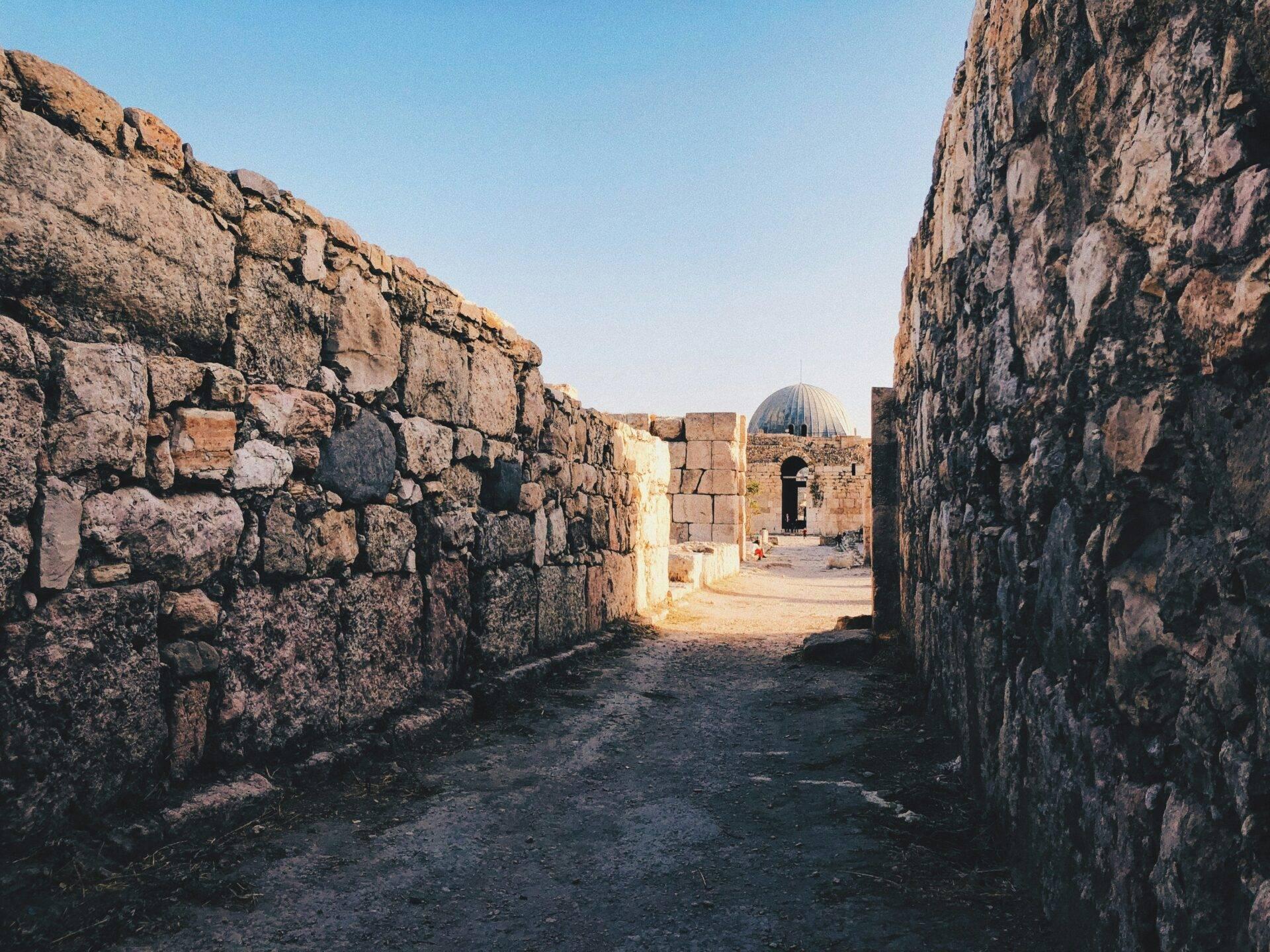 Ruines de pierre d’une forteresse historique avec dôme architectural au centre, sous ciel dégagé