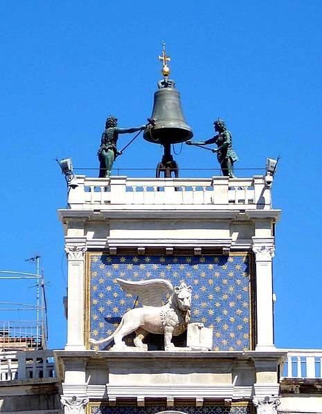 Torre dell’Orologio vénitienne avec son cadran étoilé, sa cloche et ses sculptures de bronze sous un ciel bleu