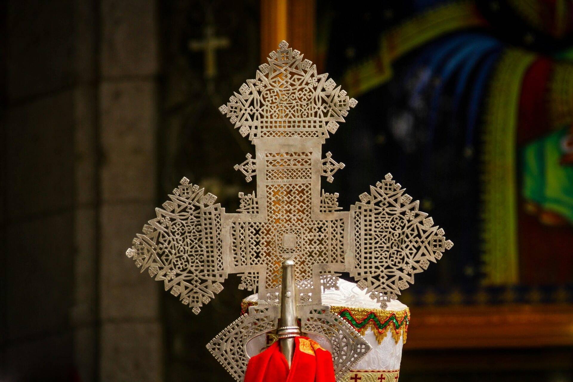 Croix ornementale en métal ajouré dans un temple éthiopien orthodoxe avec tissu rouge et décorations dorées