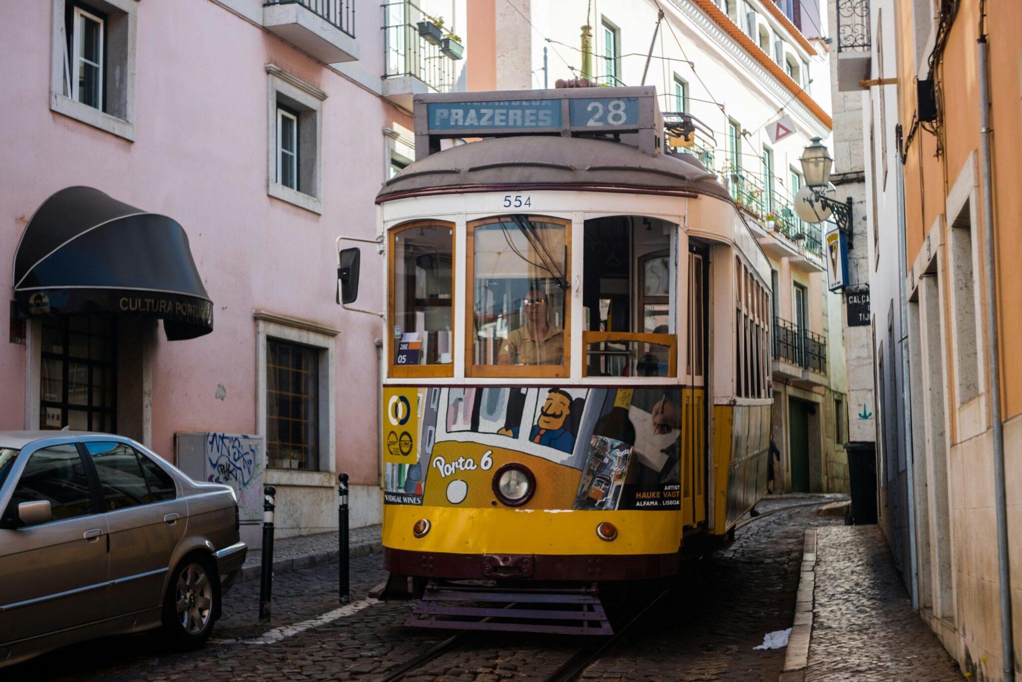 Un célèbre tramway jaune numéro 28 navigant dans une ruelle pavée étroite du quartier historique de Lisbonne