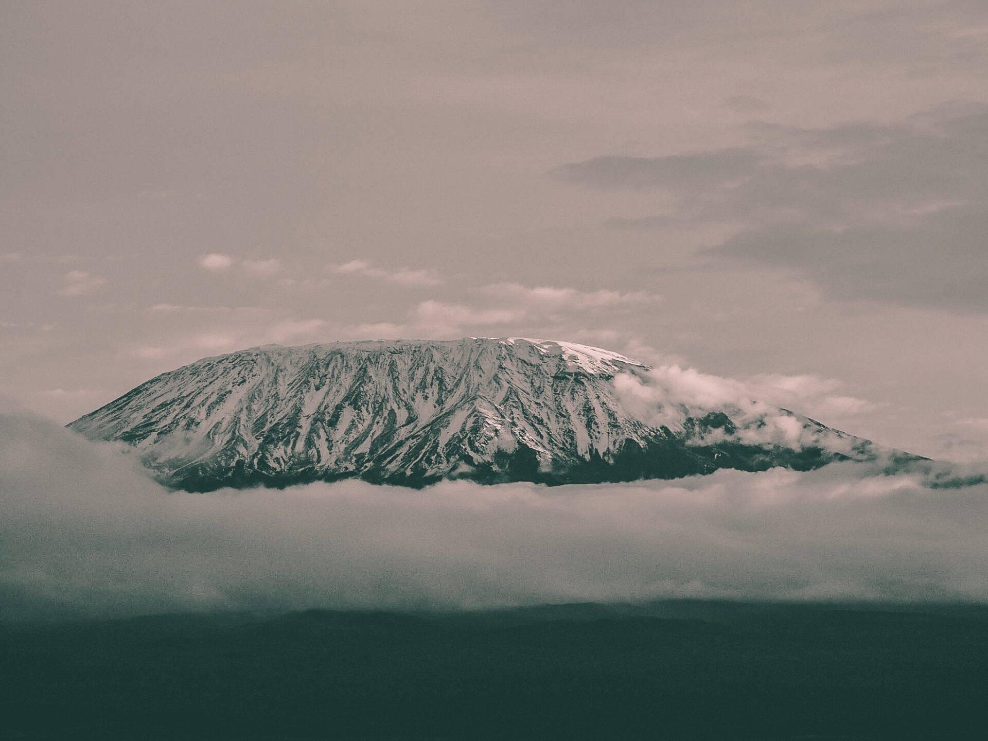 Un sommet enneigé aux pentes striées émerge partiellement des nuages, paysage montagneux majestueux en altitude