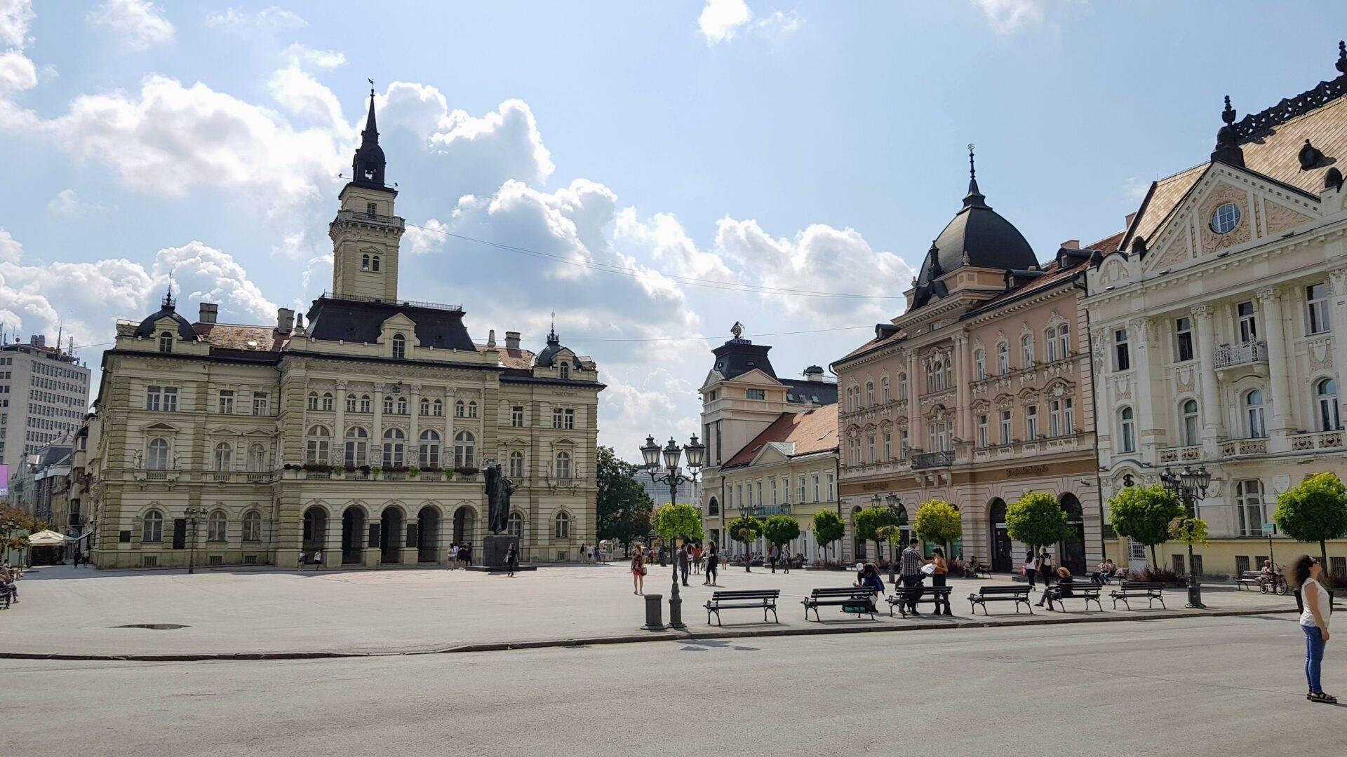 Une vaste place publique historique entourée de bâtiments d’architecture austro-hongroise avec tours et dômes