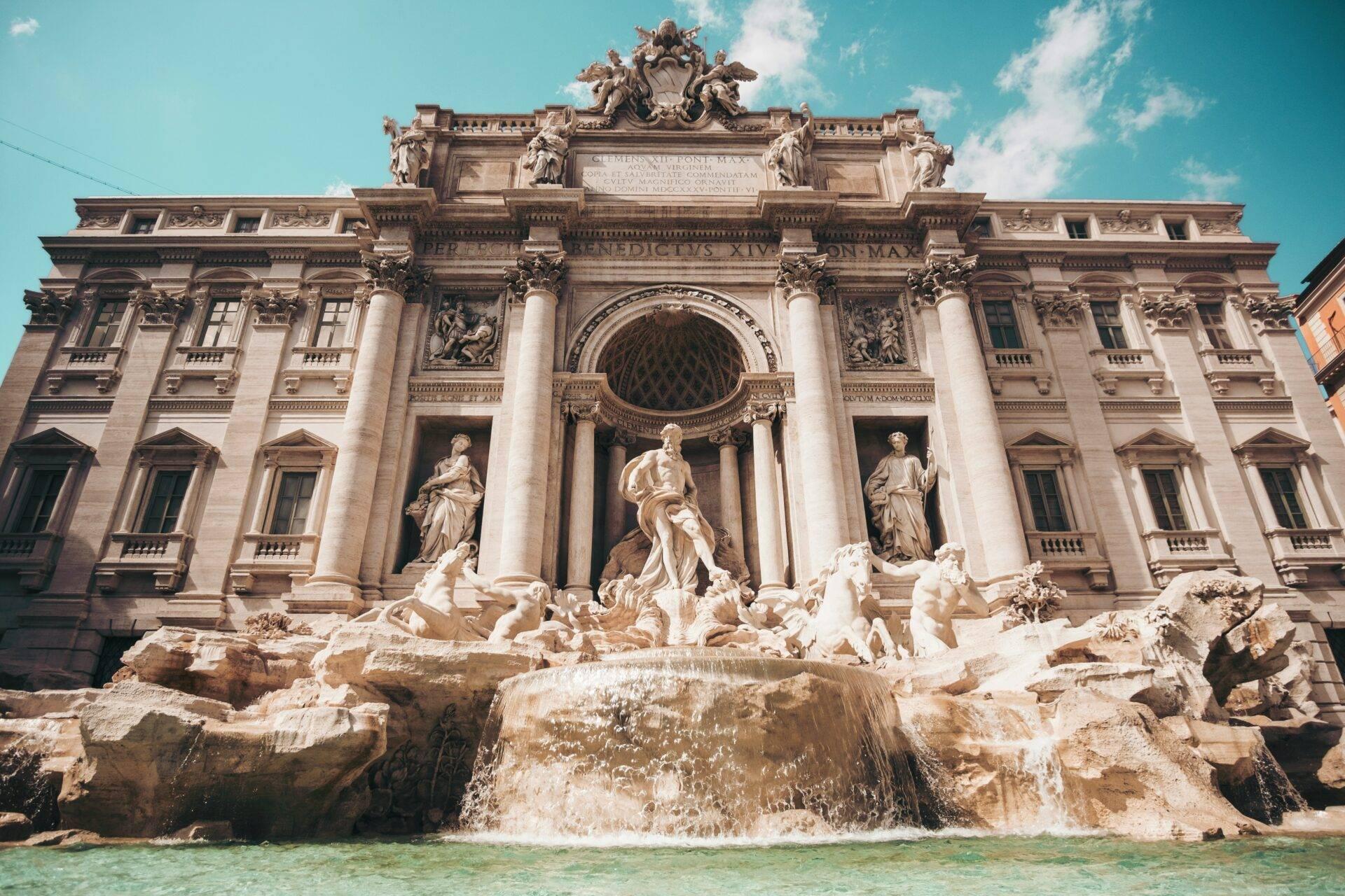 La célèbre fontaine de Trevi à Rome avec sa façade baroque imposante et ses sculptures blanches sous un ciel bleu