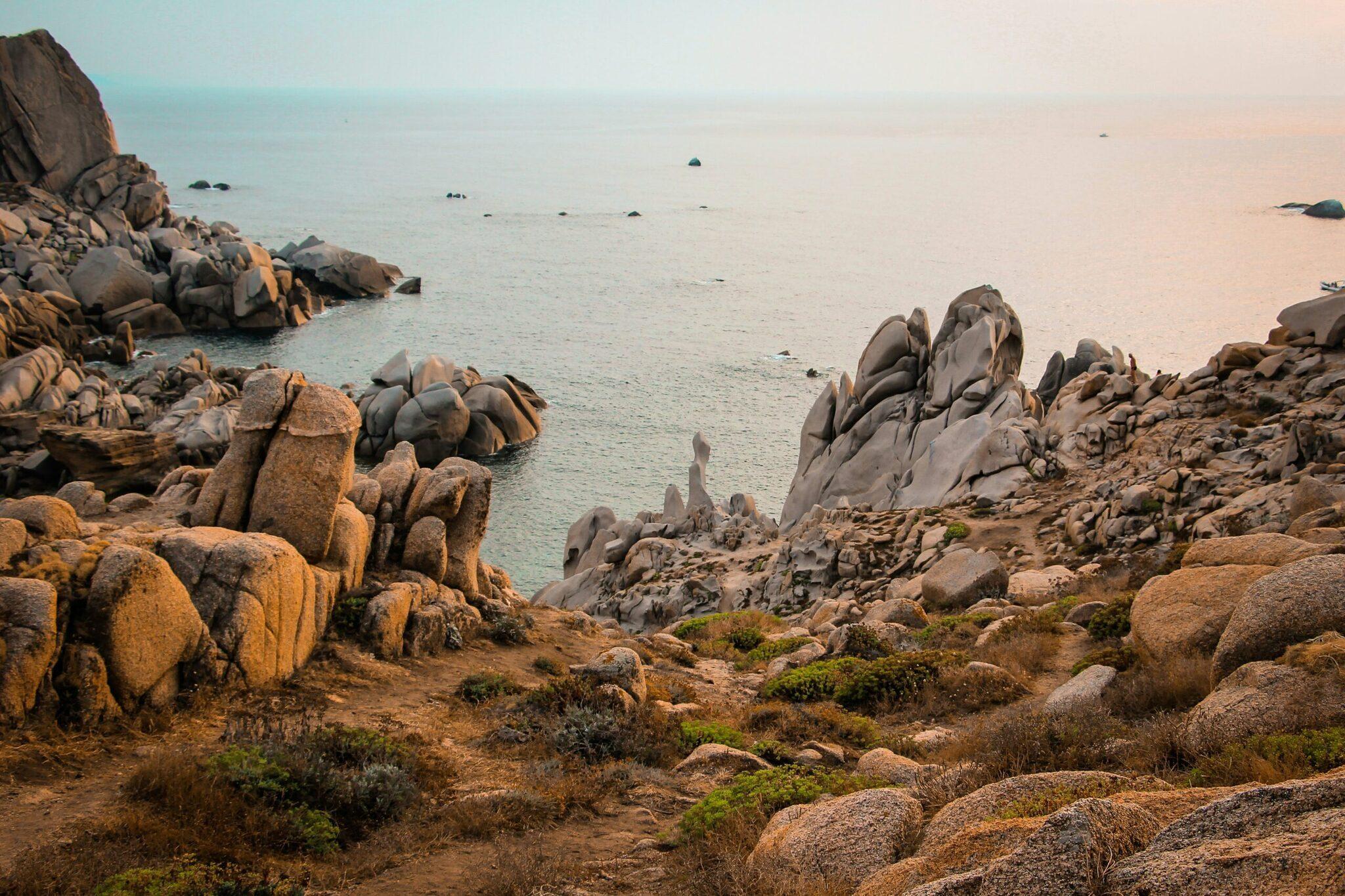 Rocky granite coastline with rounded boulders overlooking a calm turquoise bay