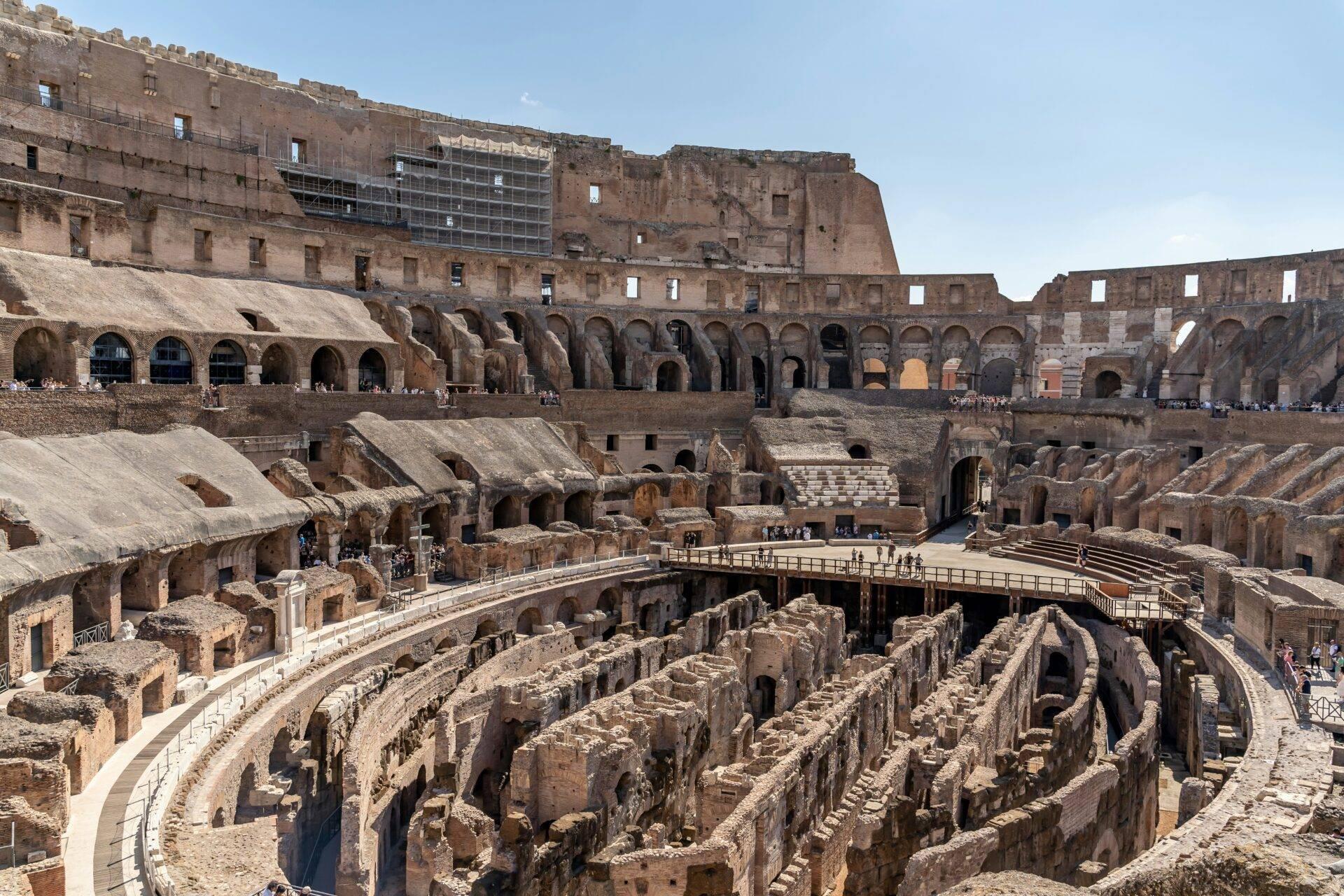 Intérieur d’un amphithéâtre romain en ruines avec arènes, gradins effondrés et arcades bien préservées