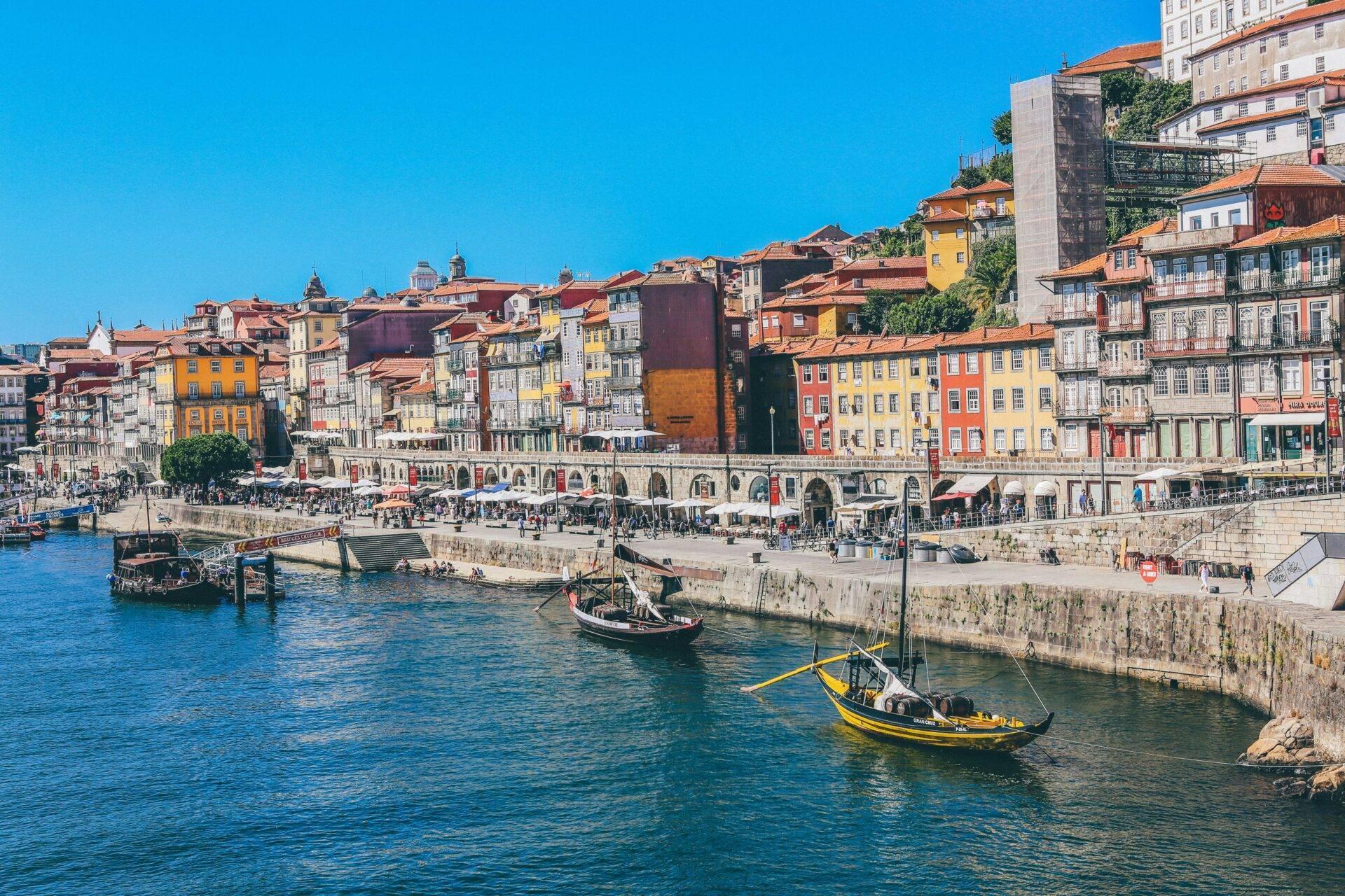 Vue panoramique d’une ville portuaire avec bâtiments colorés, bateaux traditionnels et architecture historique en bord de mer