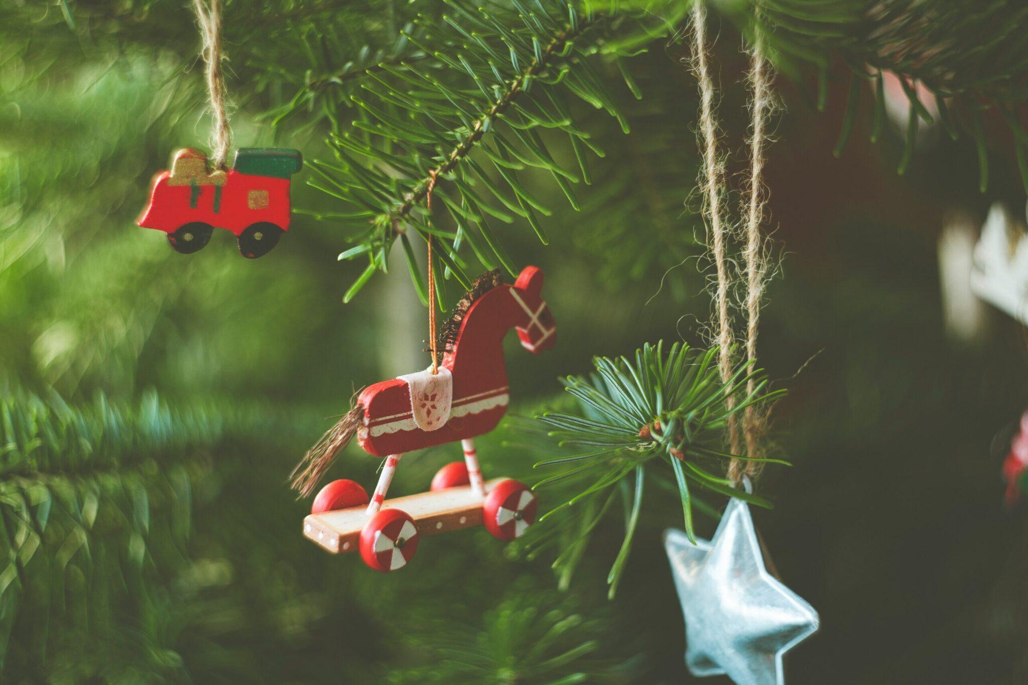 Ornements de Noël rouges suspendus aux branches de sapin vert, créant une ambiance festive chaleureuse