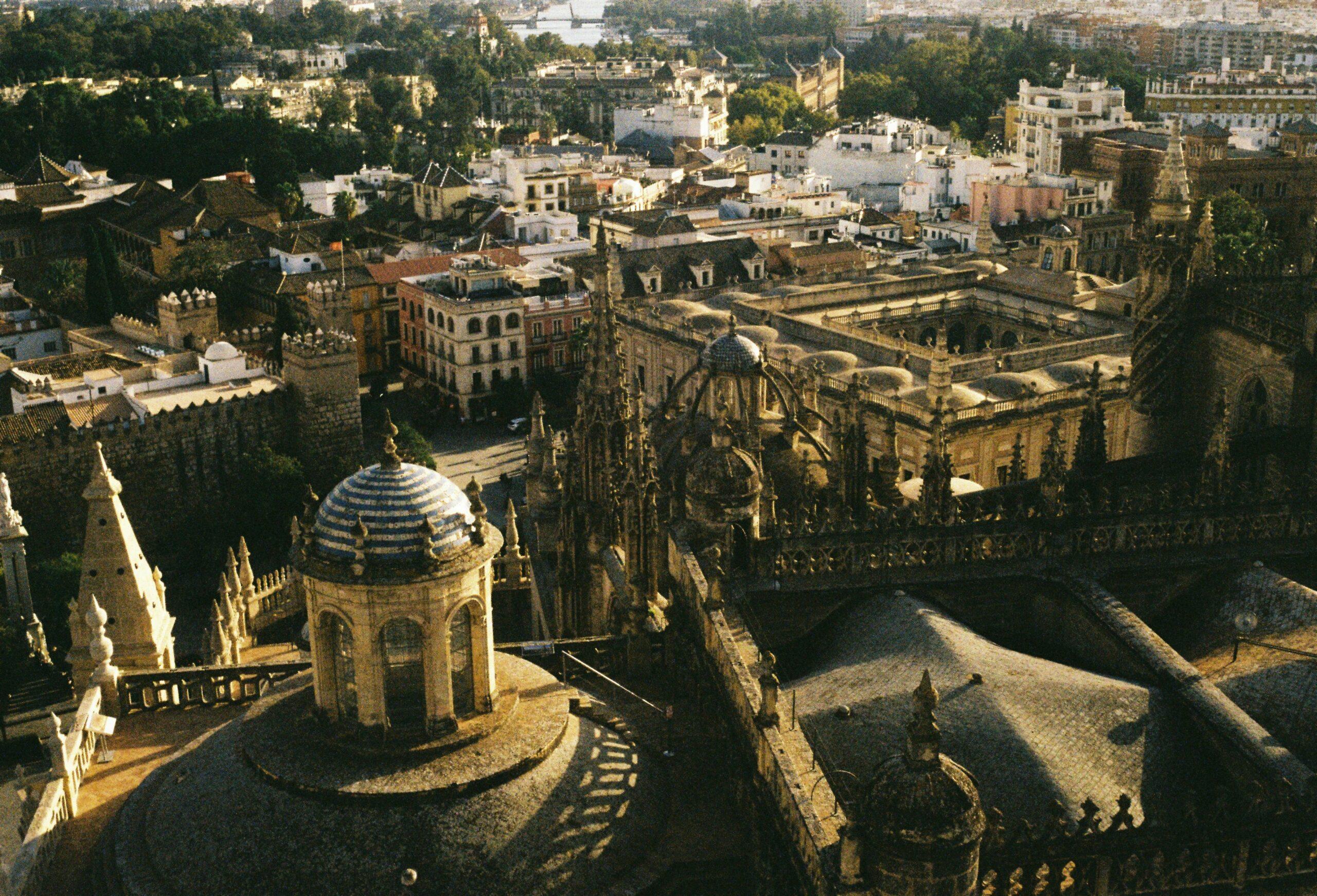 Vue aérienne de la Cathédrale de Séville avec ses toits dorés, entourée de bâtiments historiques et de jardins andalous