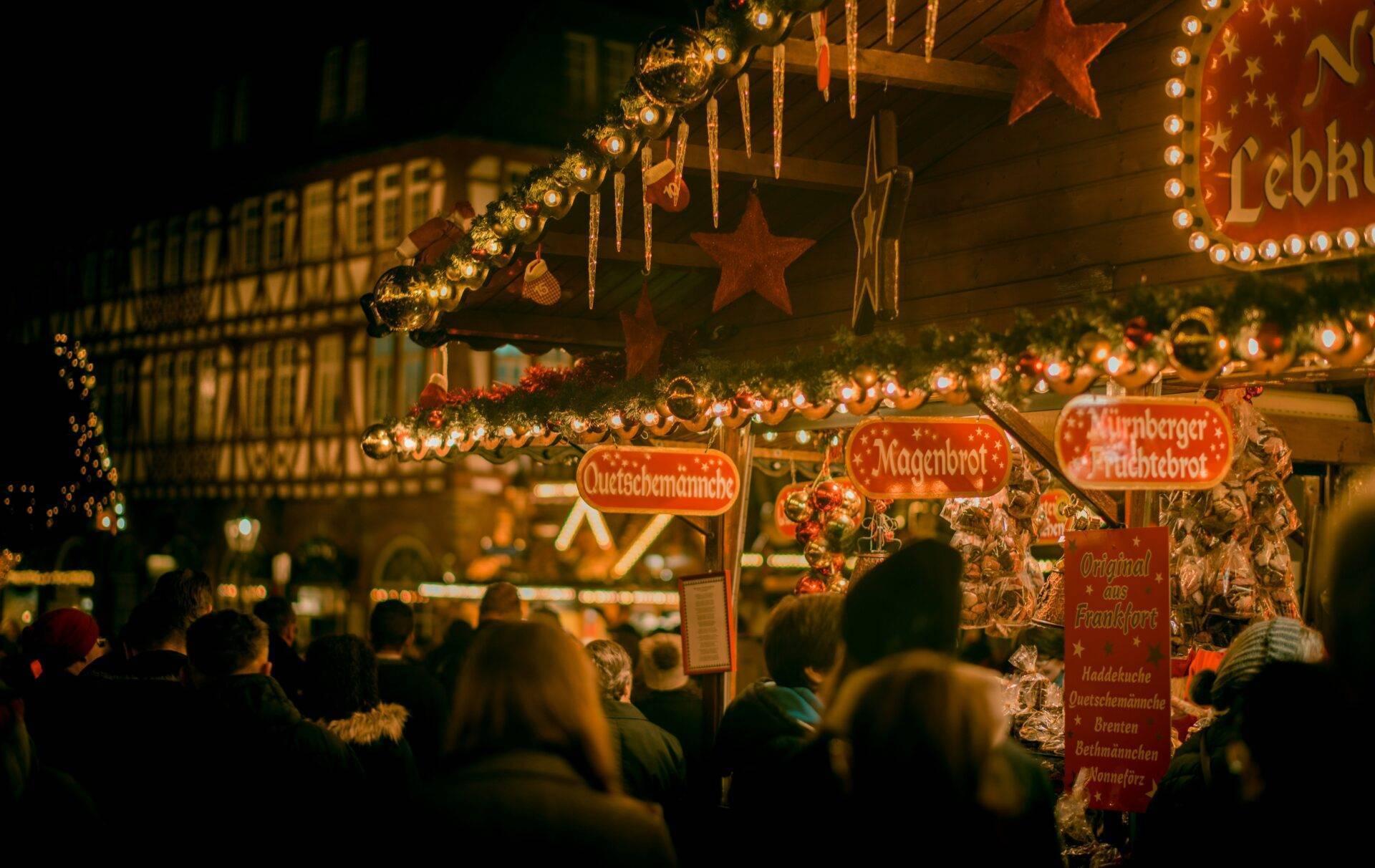 Un marché de Noël allemand illuminé la nuit avec chalets décorés, étoiles dorées et foule de visiteurs