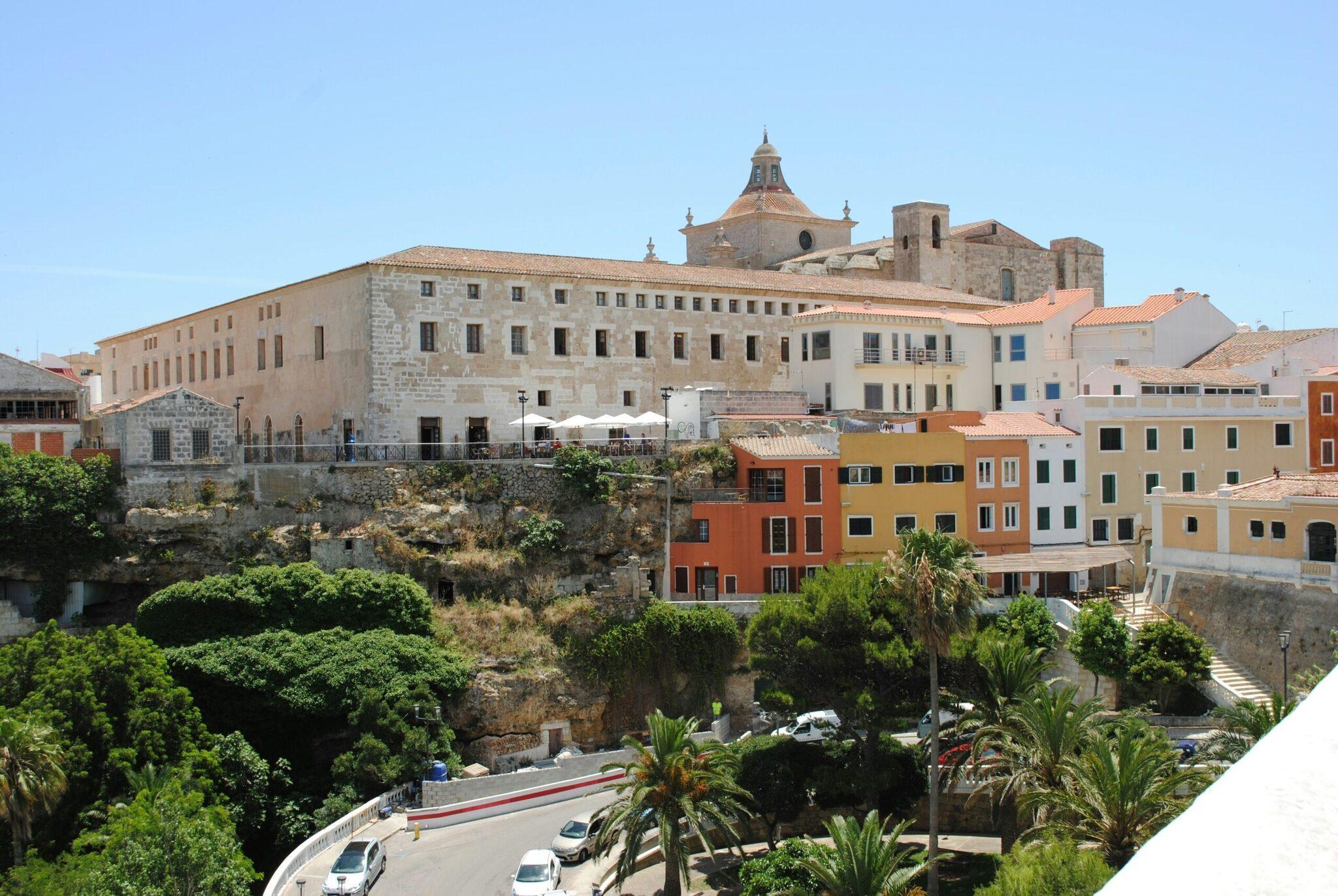Vue sur une ville côtière méditerranéenne avec église baroque, bâtiments colorés et architecture historique sur falaise