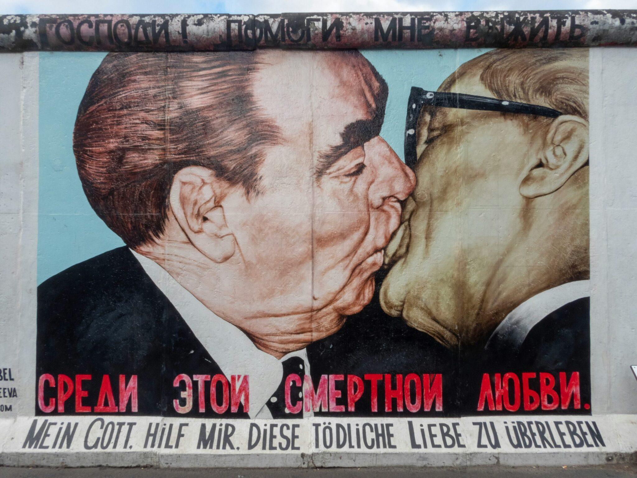 Fresque murale célèbre de deux hommes s’embrassant sur un mur de Berlin, symbole historique iconique