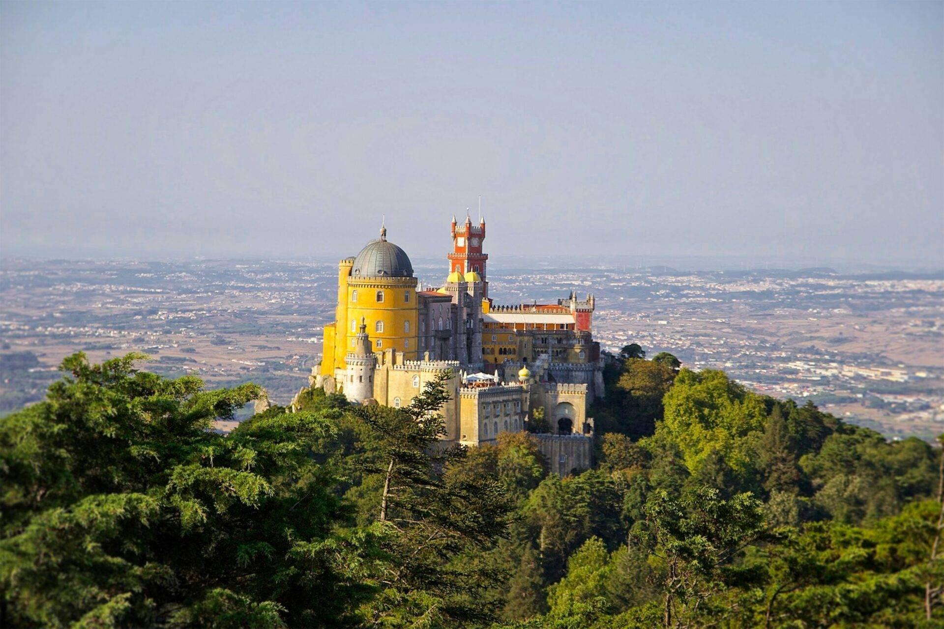 Un majestueux château coloré perché sur une colline boisée surplombant une vallée verdoyante