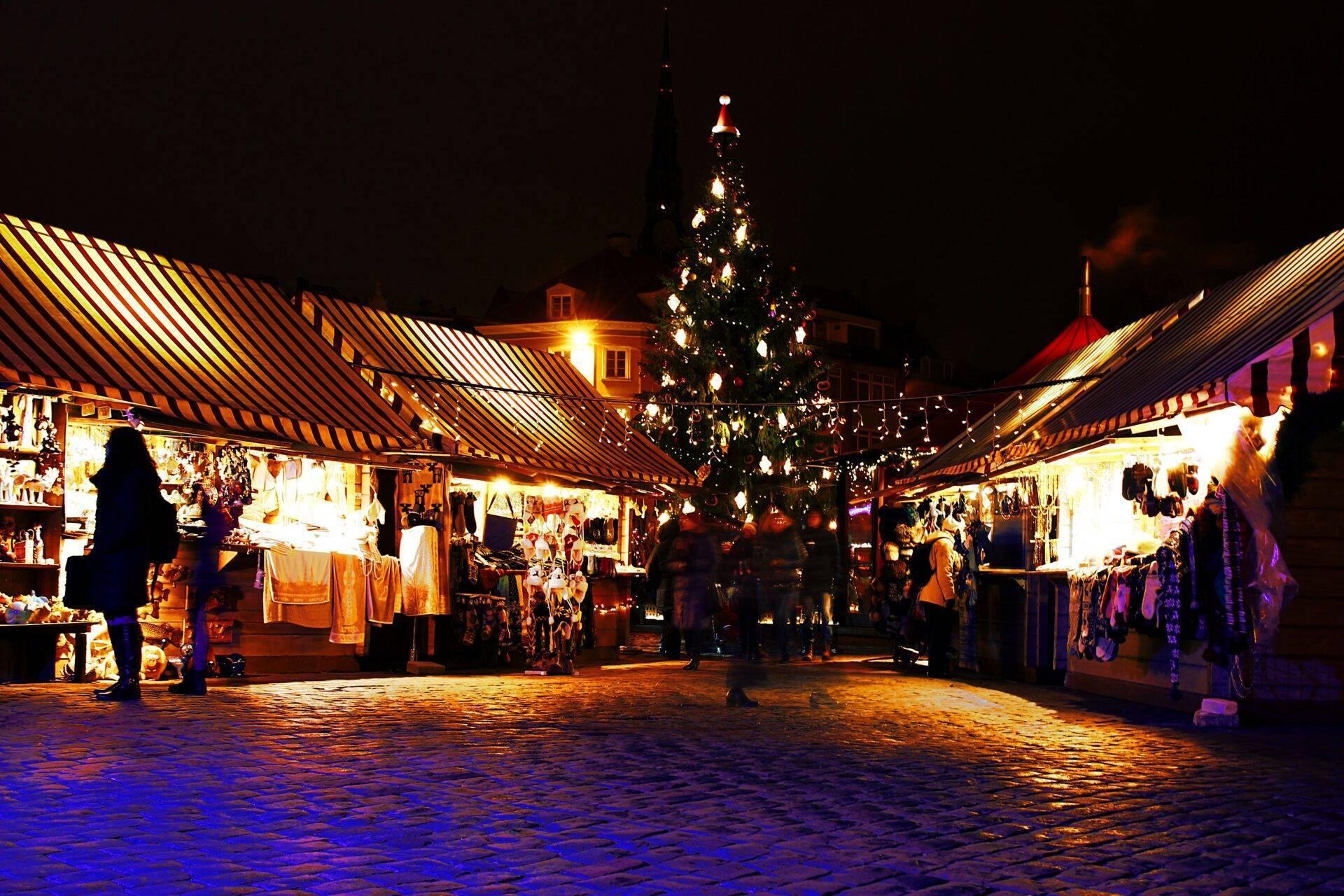 Un marché de Noël illuminé la nuit avec sapin décoré, chalets et foule de visiteurs