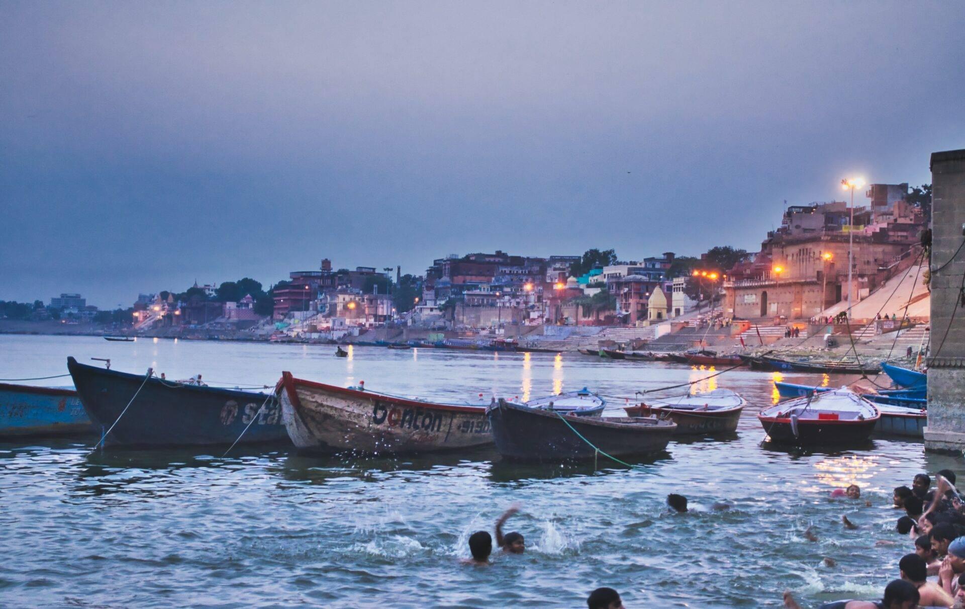 Bateaux de pêche colorés amarrés dans une baie au crépuscule avec des temples et maisons en arrière-plan