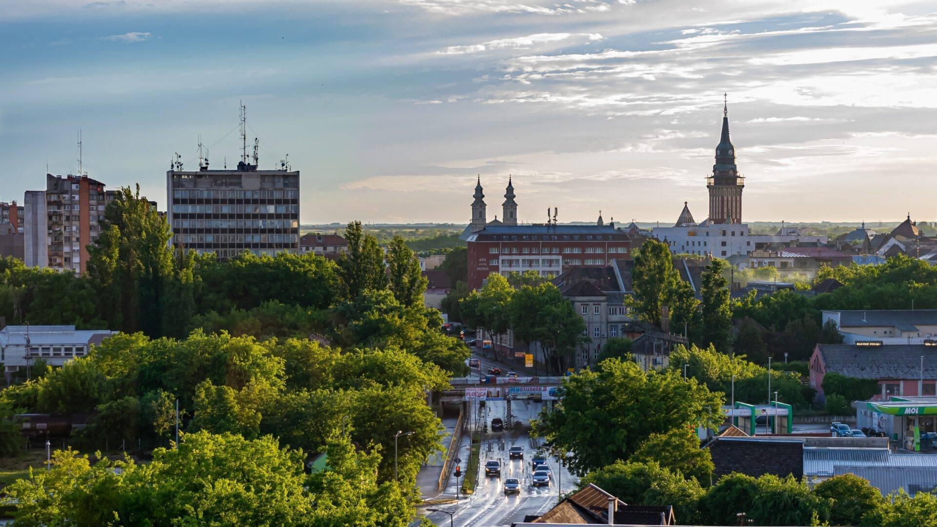 Vue panoramique d’une ville européenne avec cathédrale, immeubles modernes et végétation luxuriante sous ciel dégagé