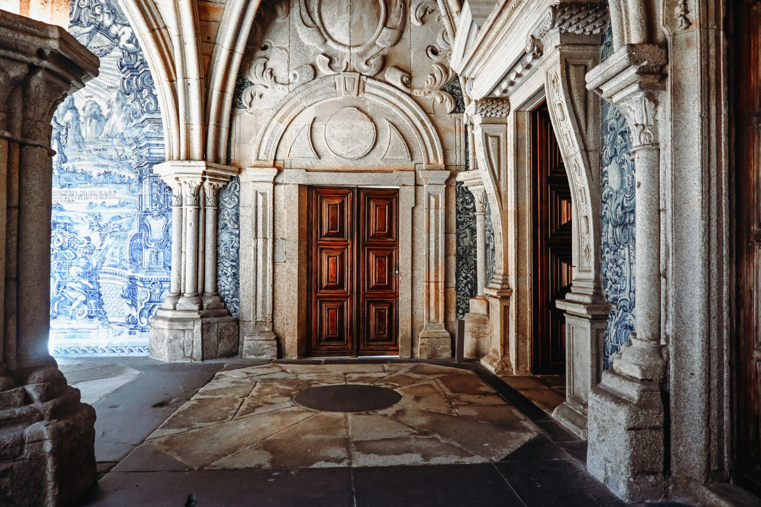 Couloir baroque orné de carreaux bleus portuguais et de portes en bois rouge, avec colonnes de pierre sculptée