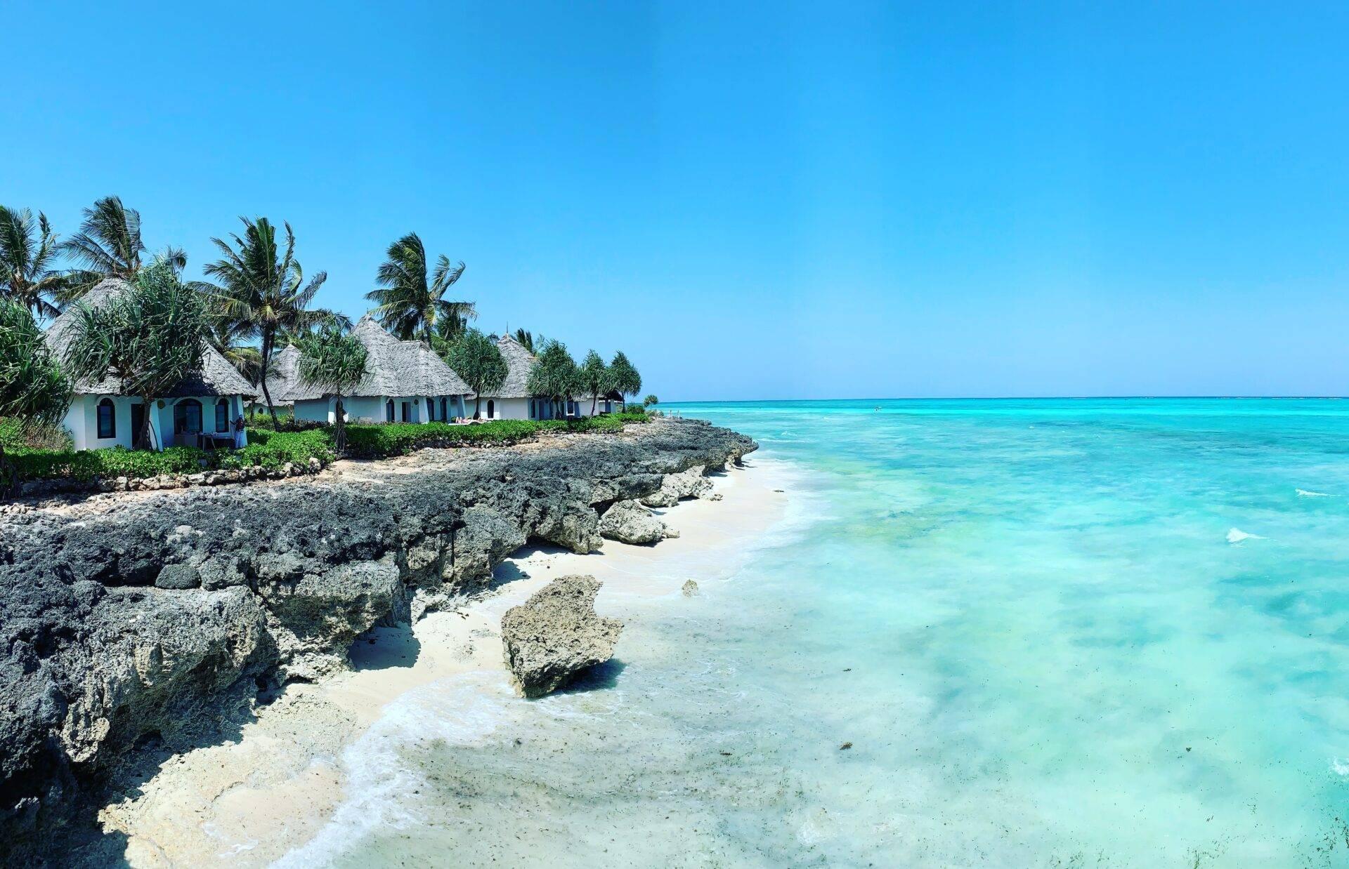 Petits bungalows aux toits de chaume face à une lagune turquoise et des rochers coralliens dans un décor tropical