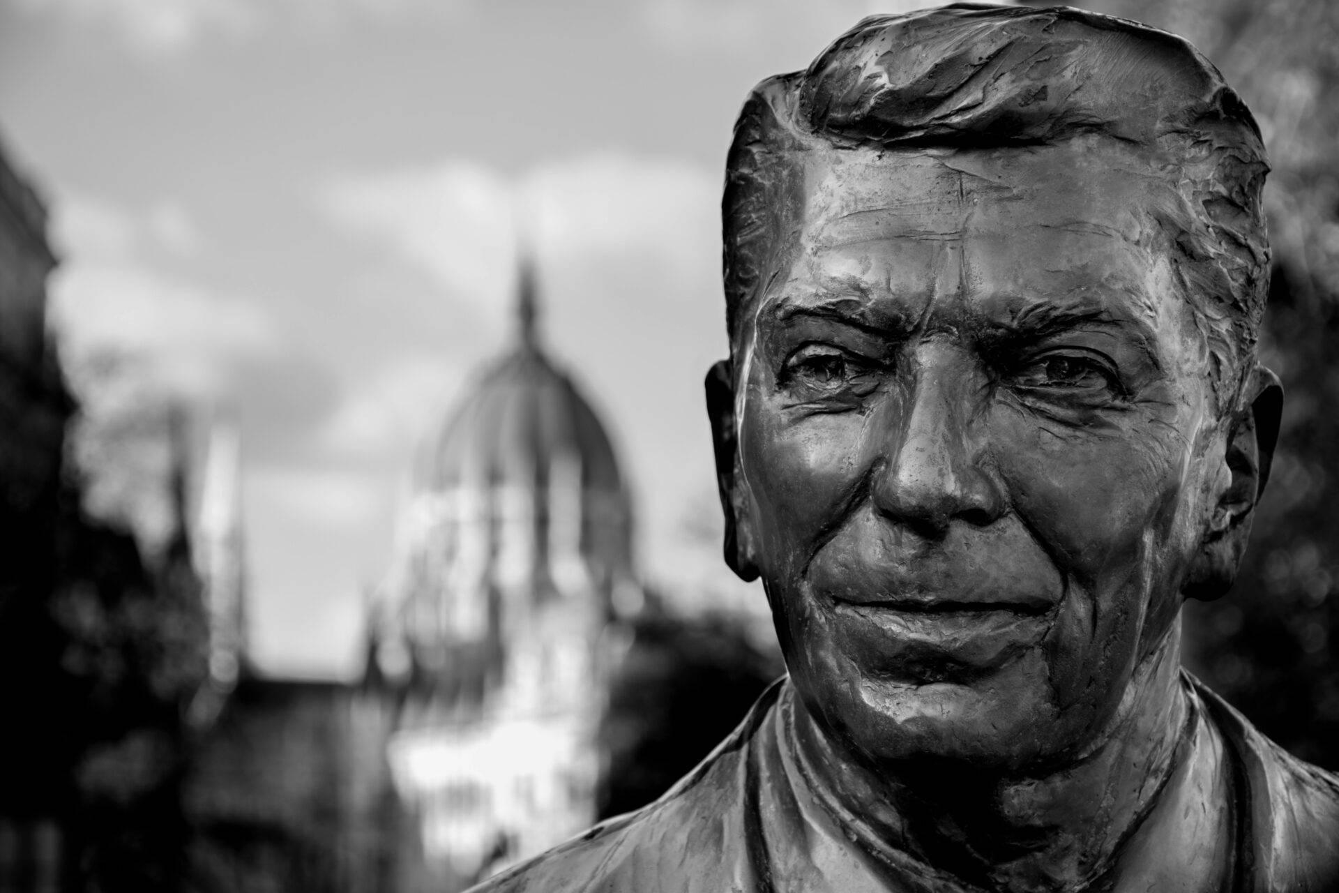 Statue en bronze d’un homme avec édifice religieux à dôme en arrière-plan, ambiance urbaine hivernale