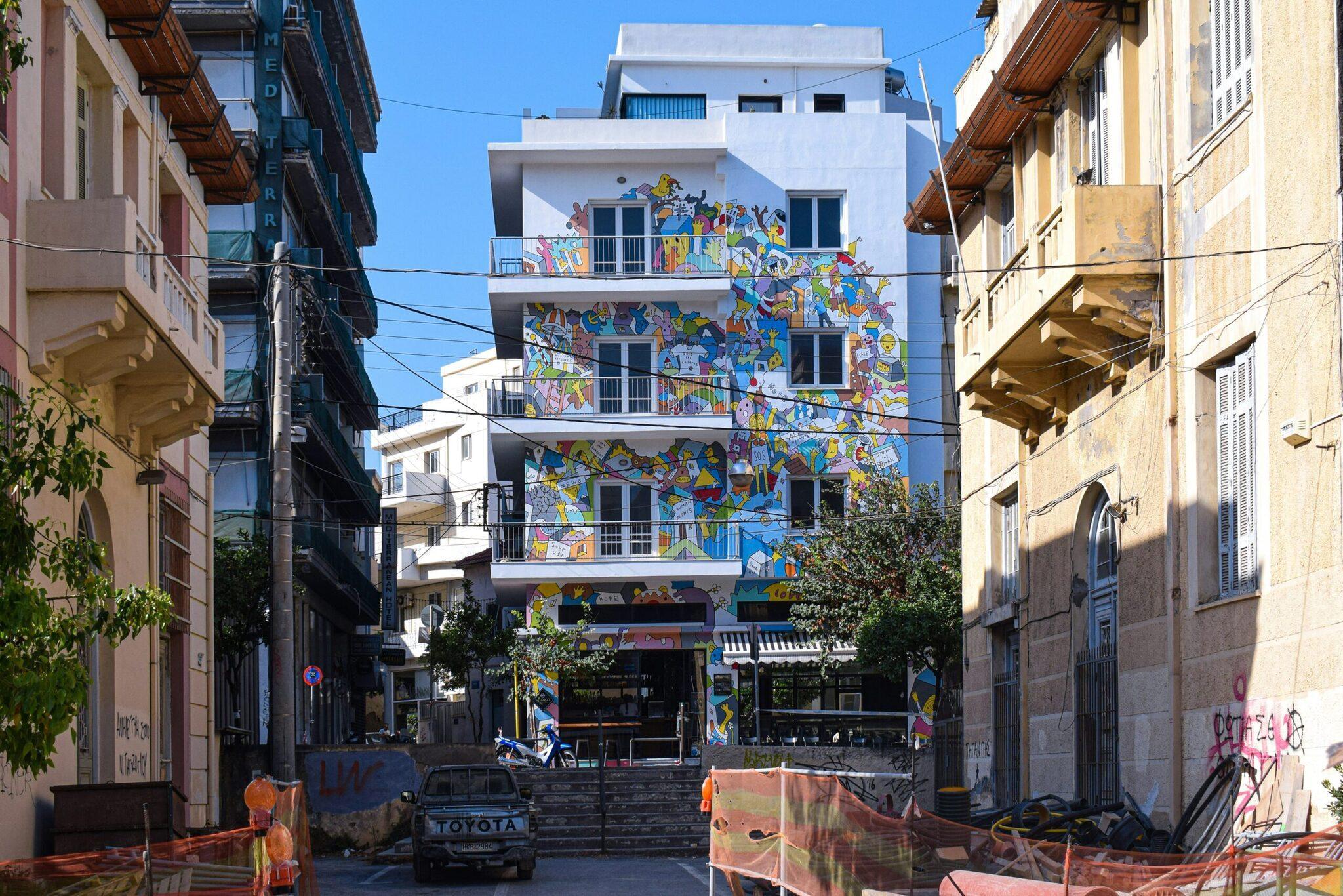 Modern building with colourful walls covered in street art in a narrow alley of a Mediterranean city