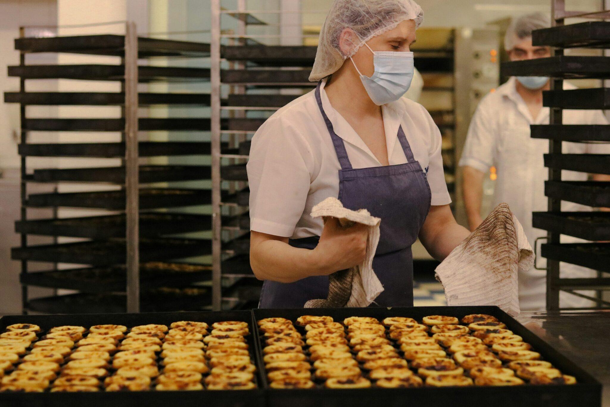 Une boulangère en uniforme de travail présente des biscuits fraîchement cuits dans une usine alimentaire
