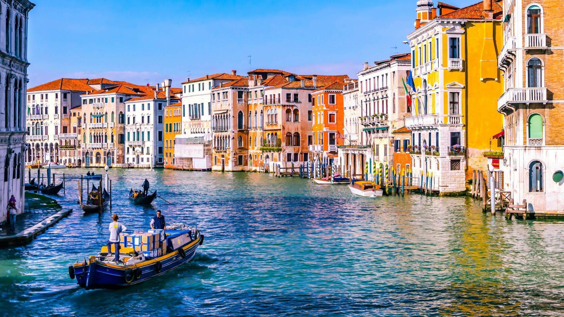 Vue panoramique du Grand Canal avec ses bâtiments colorés, gondoles et eau turquoise sous ciel bleu