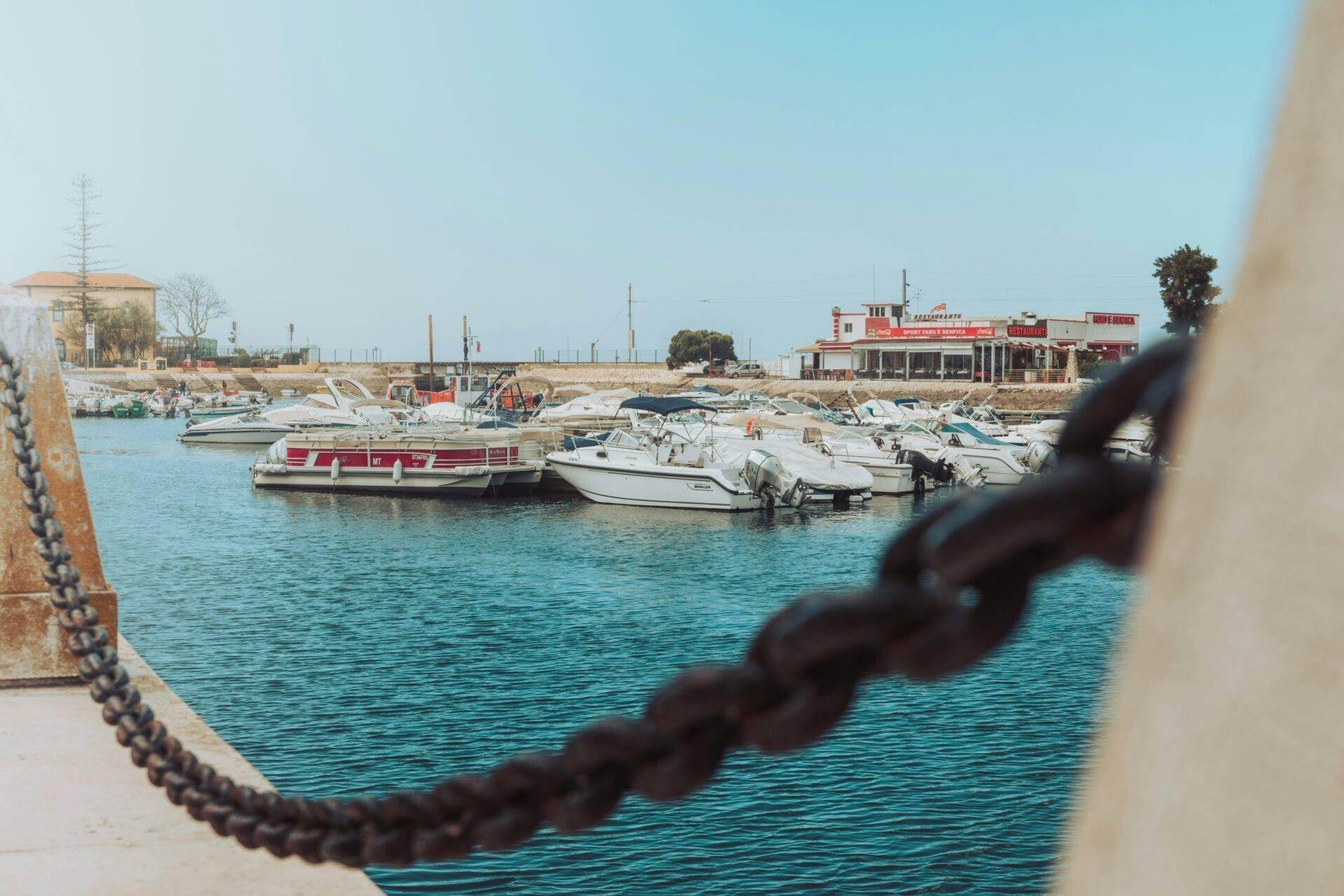 Un petit port méditerranéen avec bateaux de pêche et restaurant côtier sous un ciel dégagé