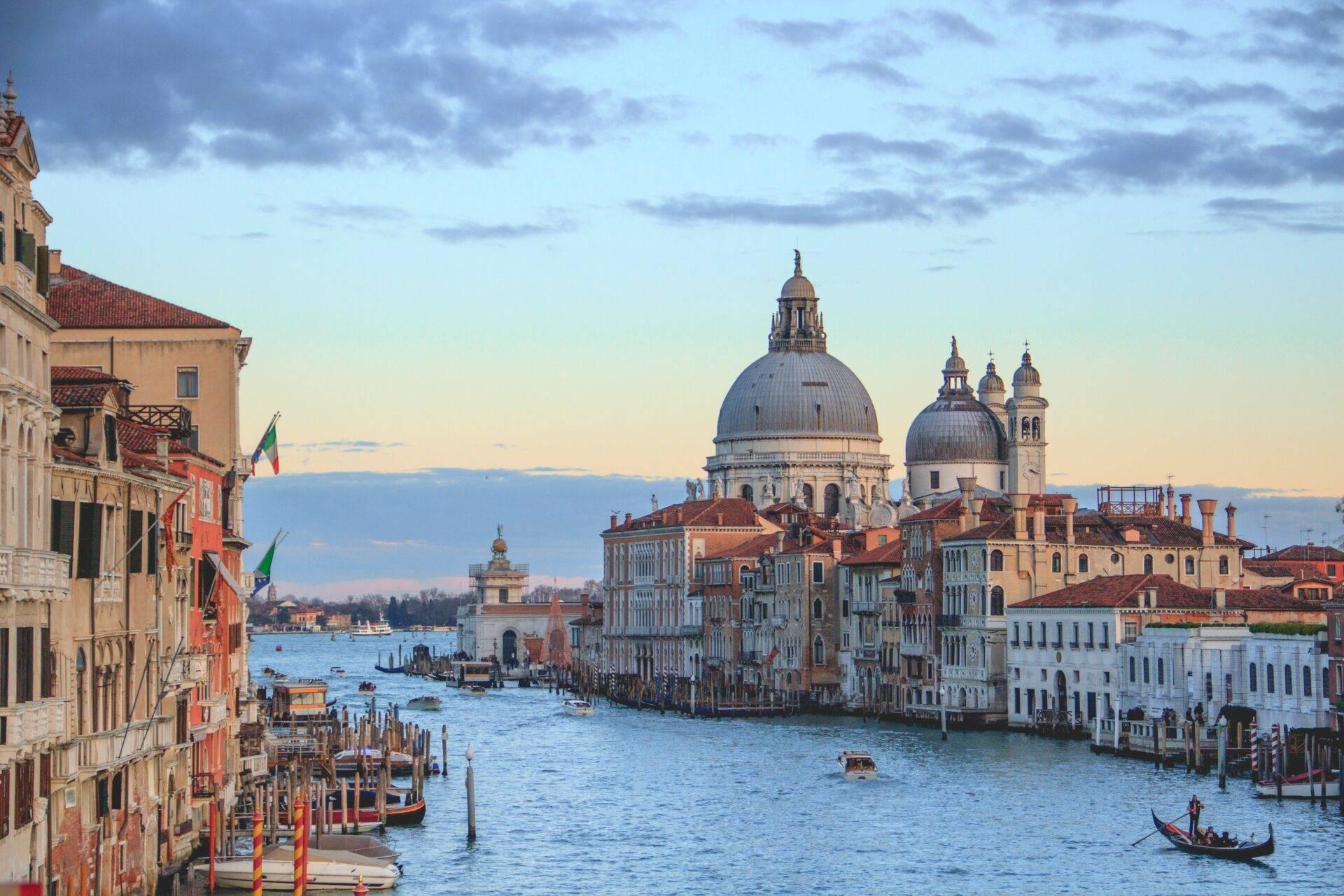 Vue sur le Grand Canal avec basilique à dôme, palais vénitiens et gondole, architecture historique italienne au crépuscule