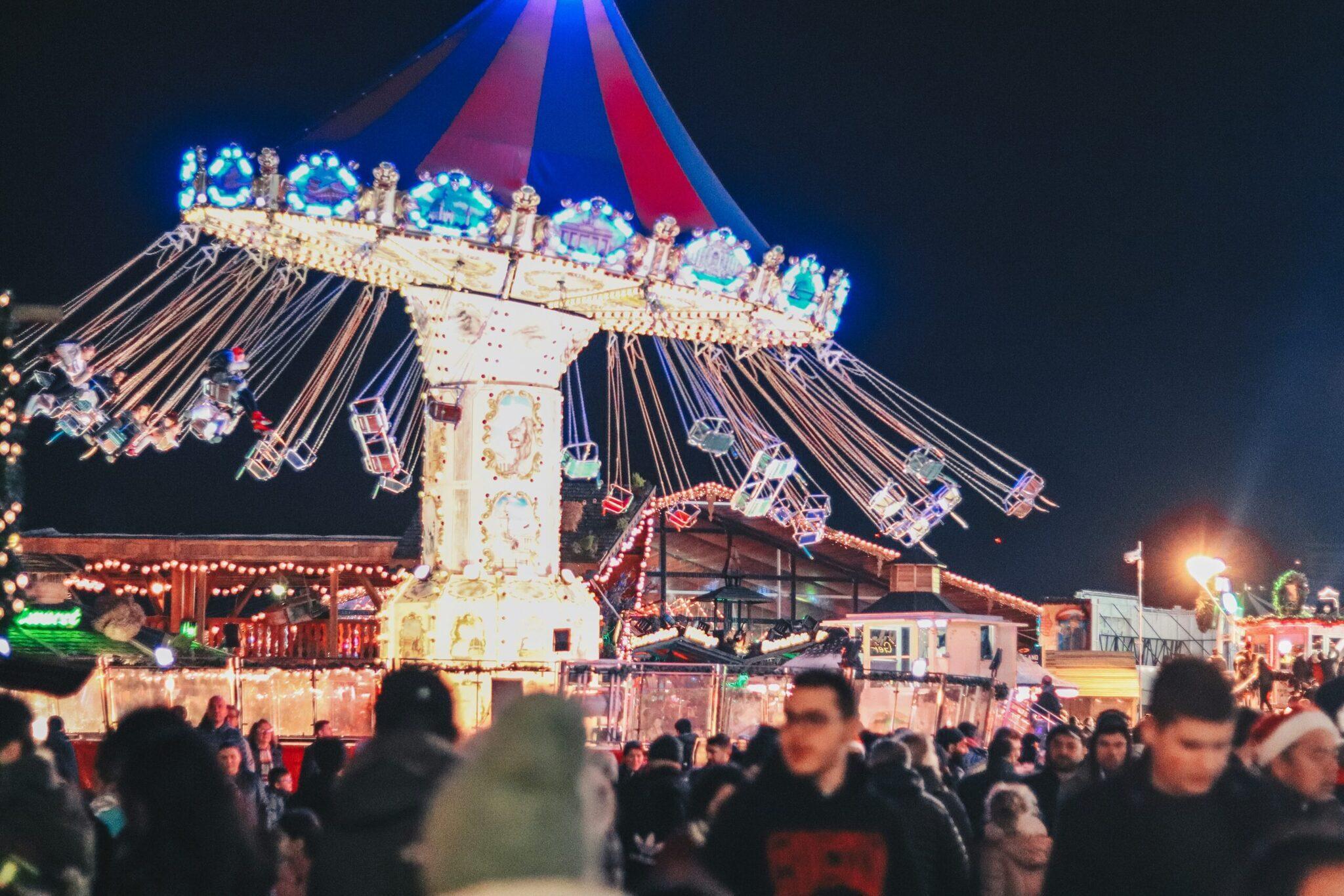 Une grande chaise volante illuminée la nuit dans un marché de Noël festif bondé de visiteurs