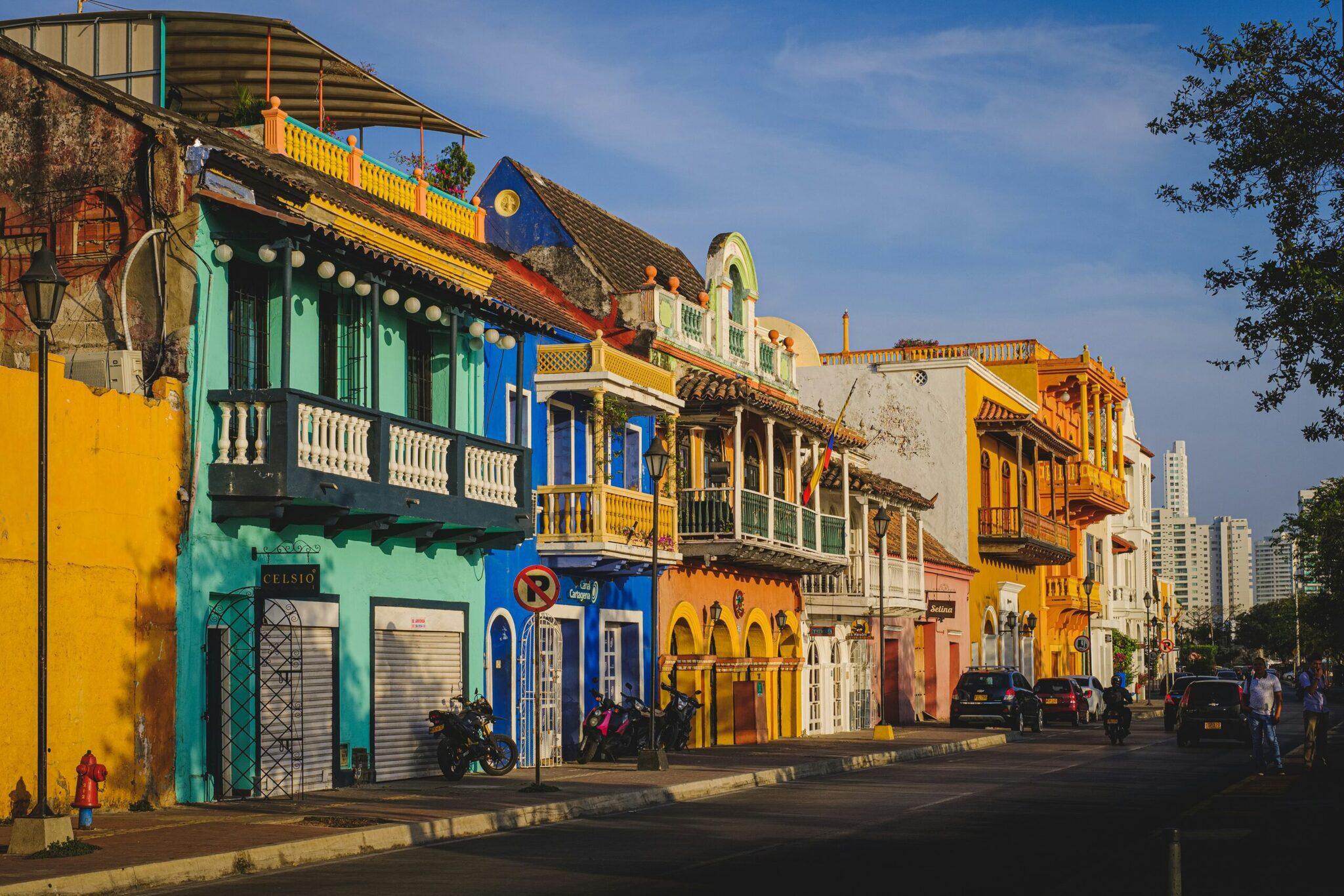 Une rue colorée de maisons coloniales aux façades jaunes, bleues et vertes avec balcons traditionnels en bois