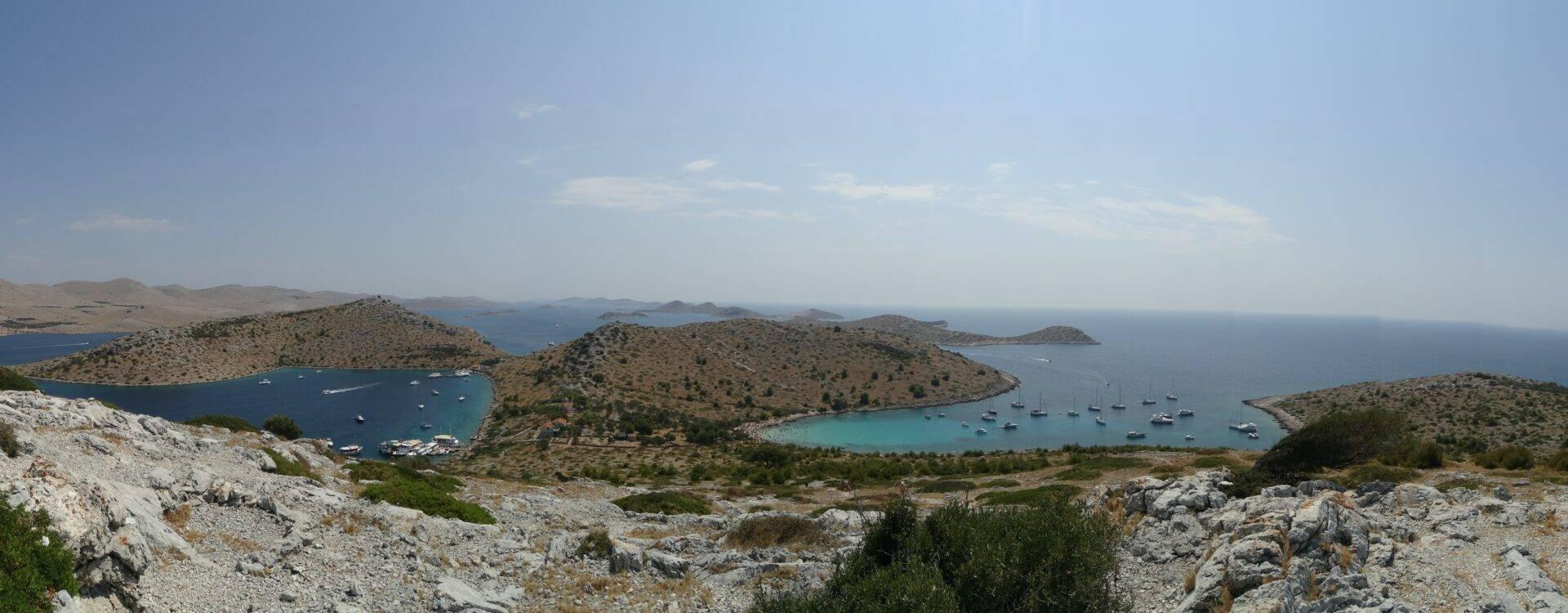 Vue panoramique d’une baie méditerranéenne avec îles boisées, eaux turquoise et voiliers ancrés
